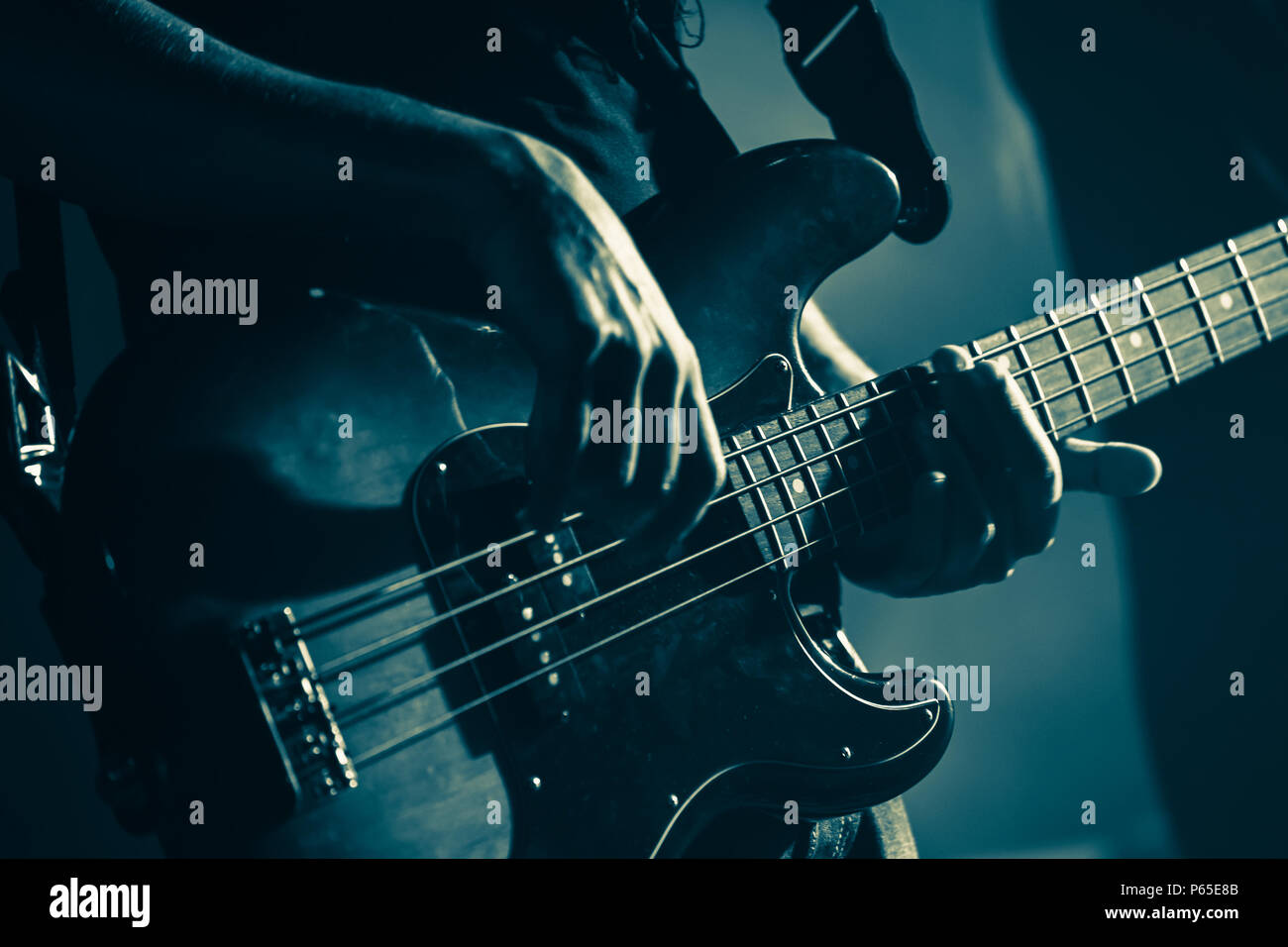 Electric bass guitar player hands, live music theme, stylized green toned photo Stock Photo