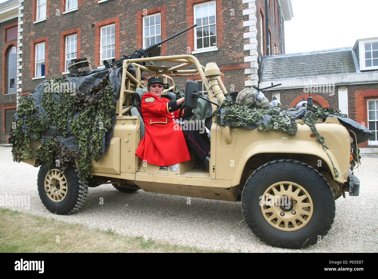 Chelsea pensioner Monica Parrott, who drove Land Rover vehicles in the Women's Royal Army Corps (WRAC) between 1964-1966 whilst stationed in Aldershot, poses in an armoured Land Rover WMIK (Weapons Mounted Installation Kit) during a photocall at the Royal Hospital Chelsea in London ahead of Armed Forces Day on June 30th. Stock Photo