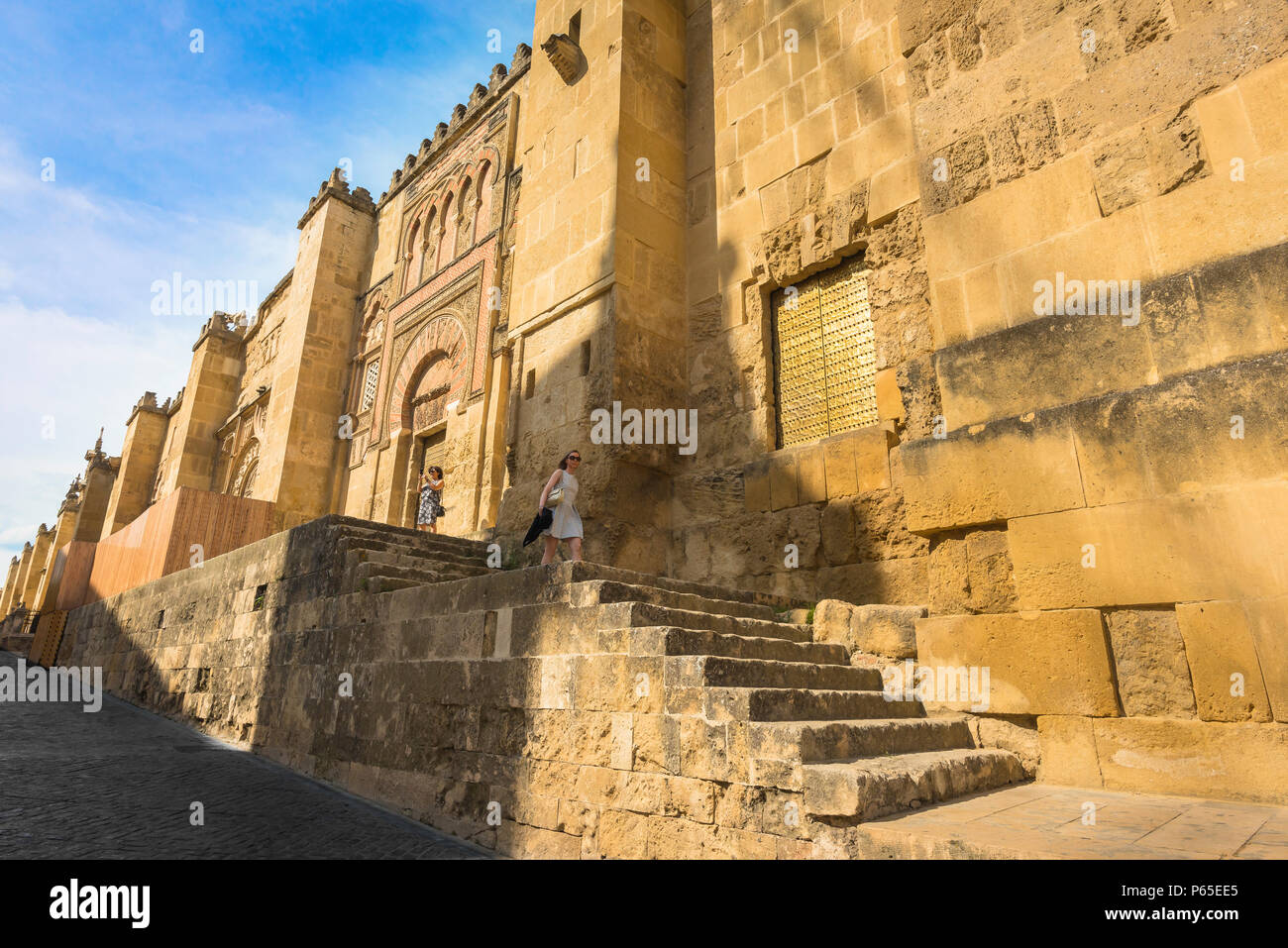 Spain Andalucia travel, a young woman descends steps alongside the west wall of the great Cathedral Mosque (La Mezquita) in Cordoba, Andalucia, Spain. Stock Photo