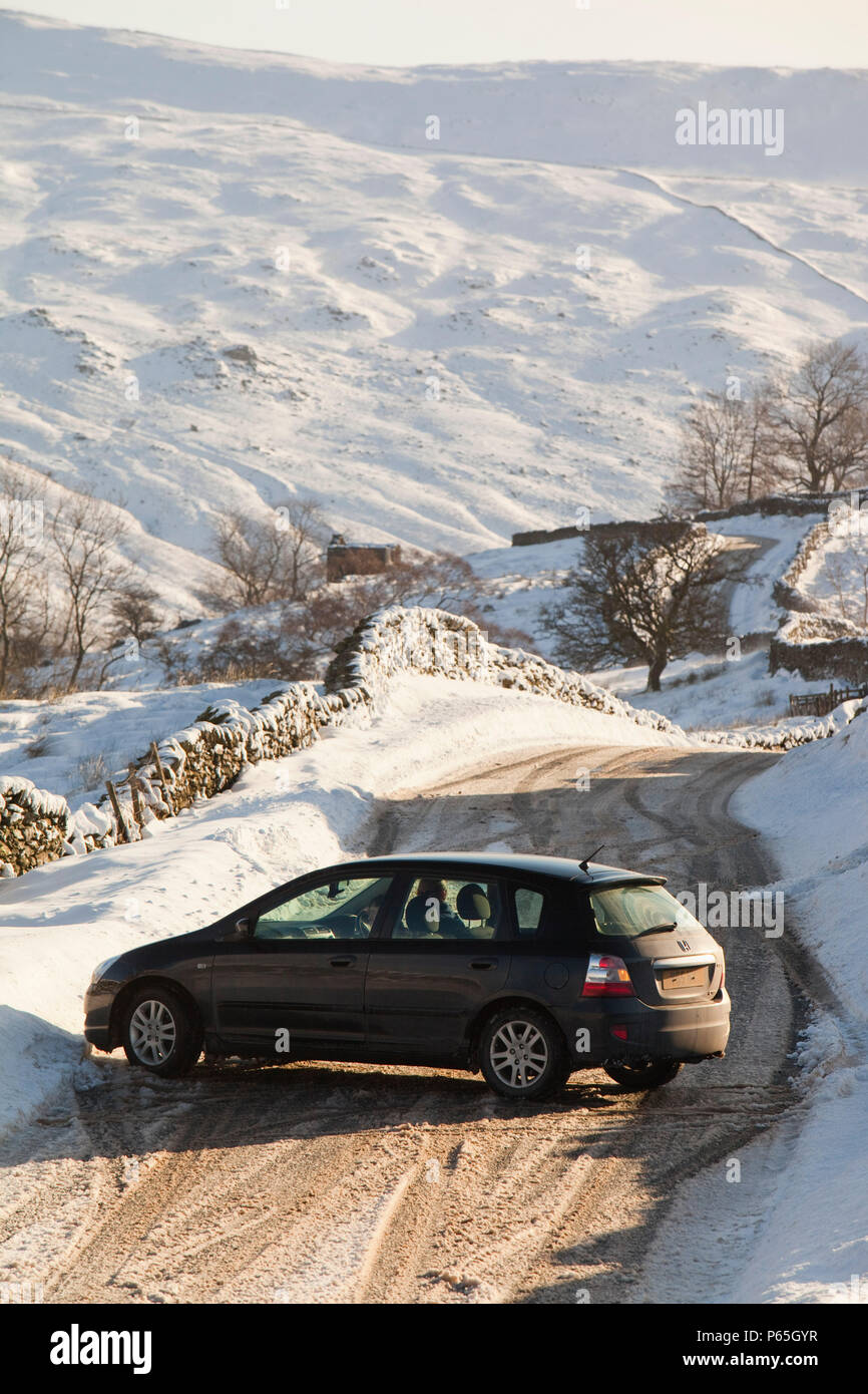 A car that skidded on ice on the Kirkstone Pass road above Windermere after it was blocked by spindrift and wind blown snow, Lake District, UK. Stock Photo