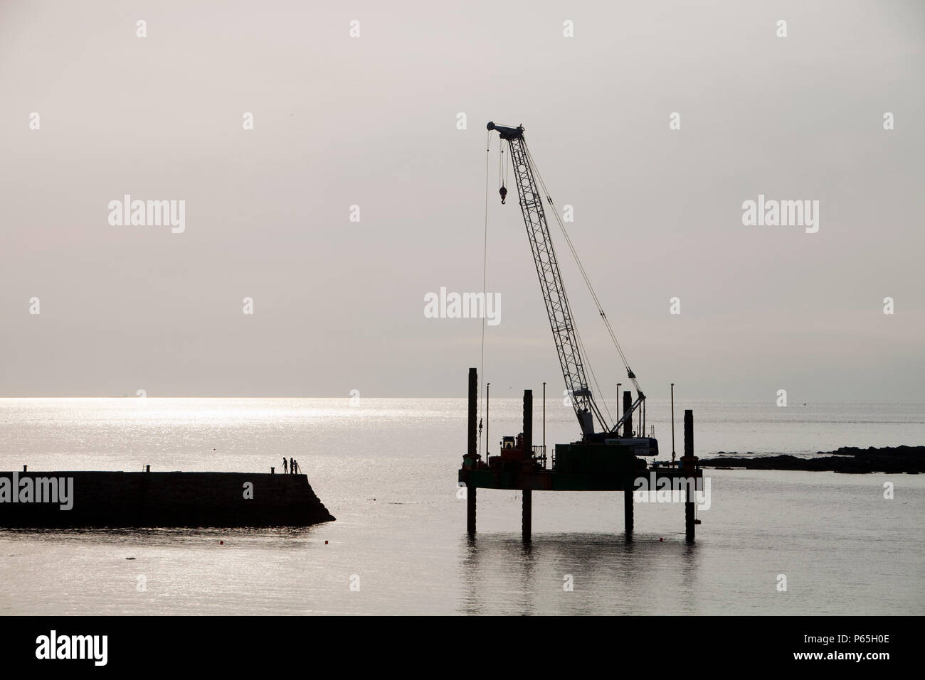 A crane on a platform off Sennen cove Harbour in Cornwall, UK Stock Photo