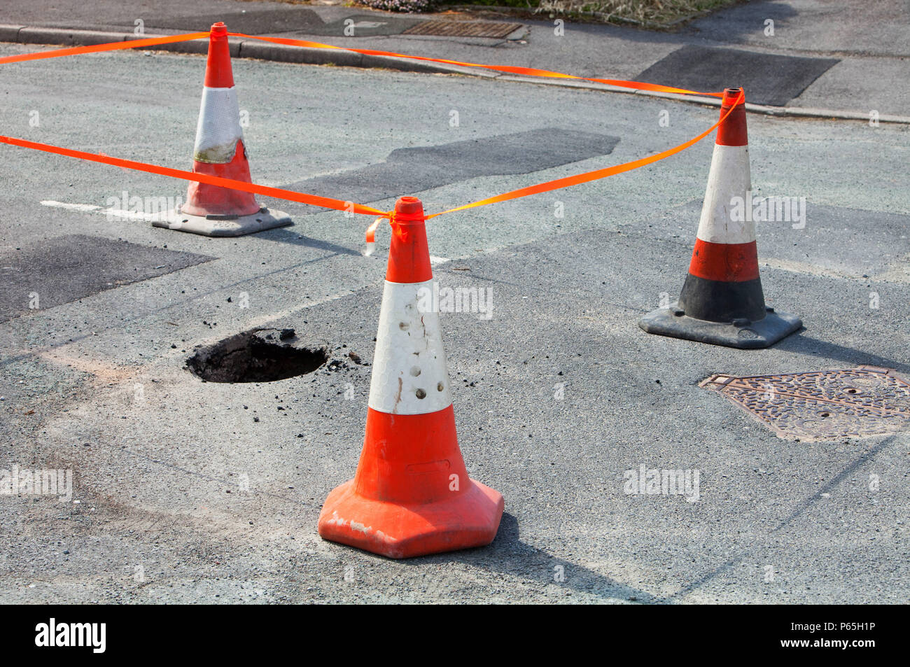 A hole opening up in the road in Ambleside, due to being undermined by flood waters. Climate change causes more extreme weather events, which leads to Stock Photo