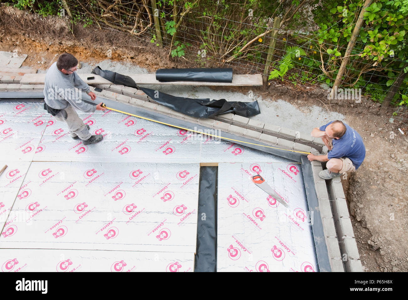 Builders lay under floor insulation into a house extension in Ambleside, UK. Stock Photo