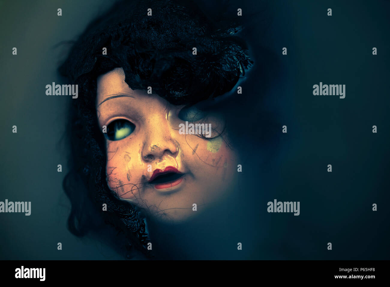 Creepy doll face in dark dirty water Stock Photo