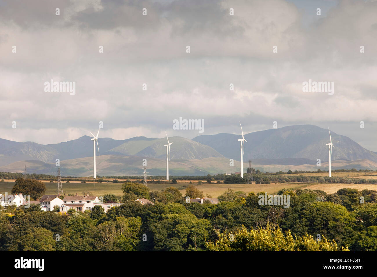 Wind turbines on the outskirts of Workington, Cumbria, UK, with the Lake District hills beyond. Stock Photo