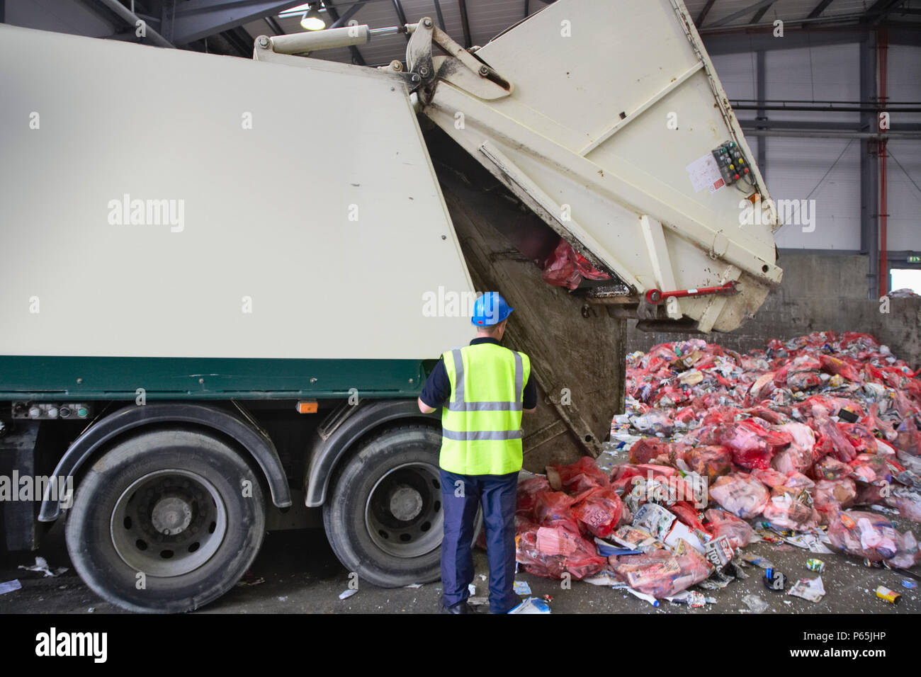 Rubbish truck emptying recycling into dumping bay at recycling centre