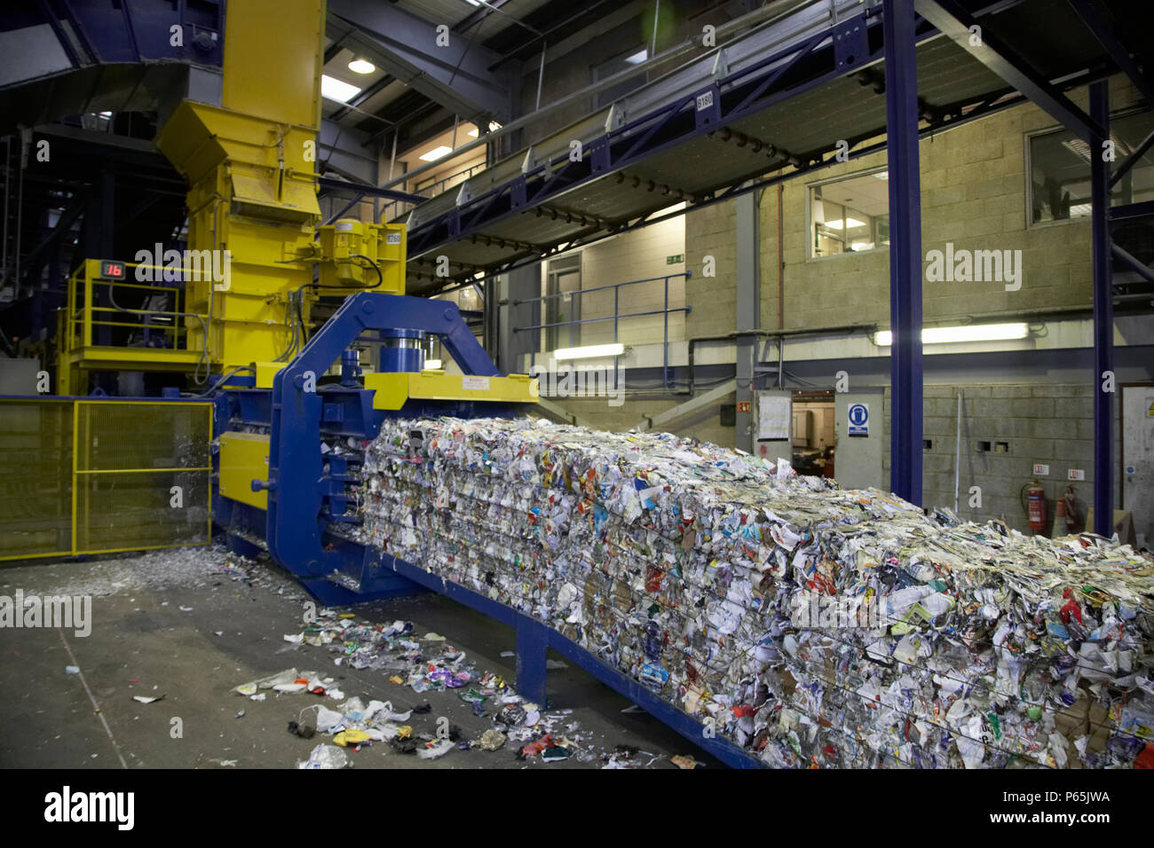 Compacted recycling coming out of compactor on to conveyor belt at recycling centre Stock Photo