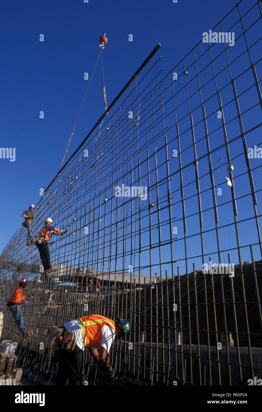 Ironworkers building rebar grid for concrete wall on freeway Stock