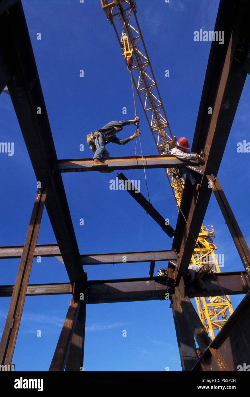 Ironworker connectors installing small steel beam between larger ones on steel high rise office