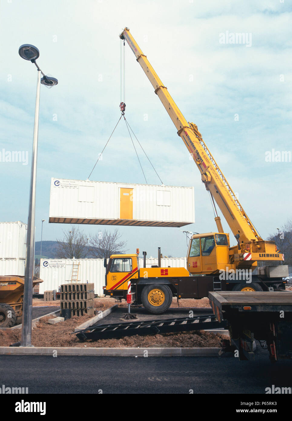 Crane lifting onto back of low loader for removal from site Stock Photo Alamy
