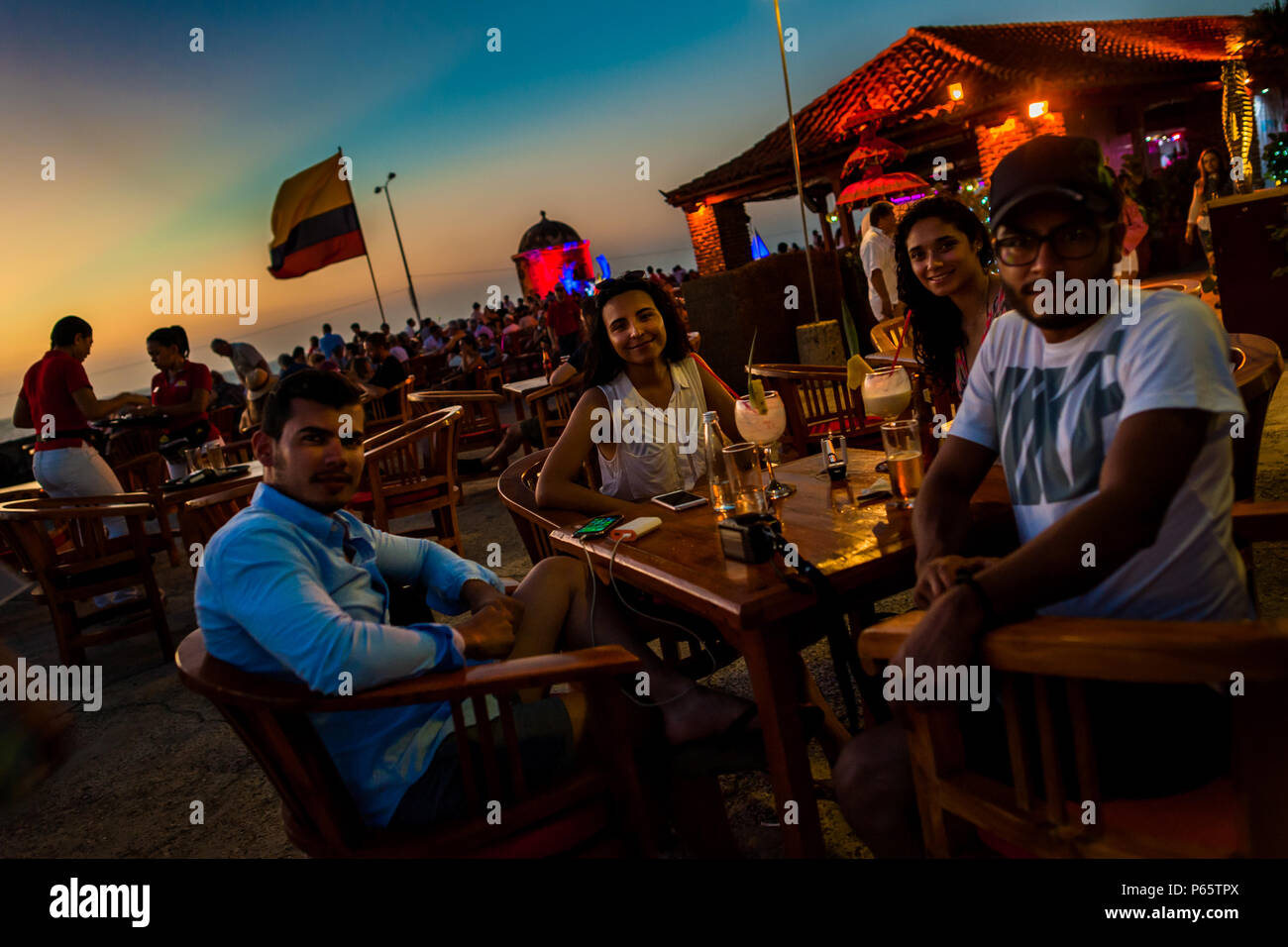 Tourists sit at Cafe del Mar restaurant located on the stone walls, surrounding the colonial walled city, at twilight in Cartagena, Colombia. Stock Photo