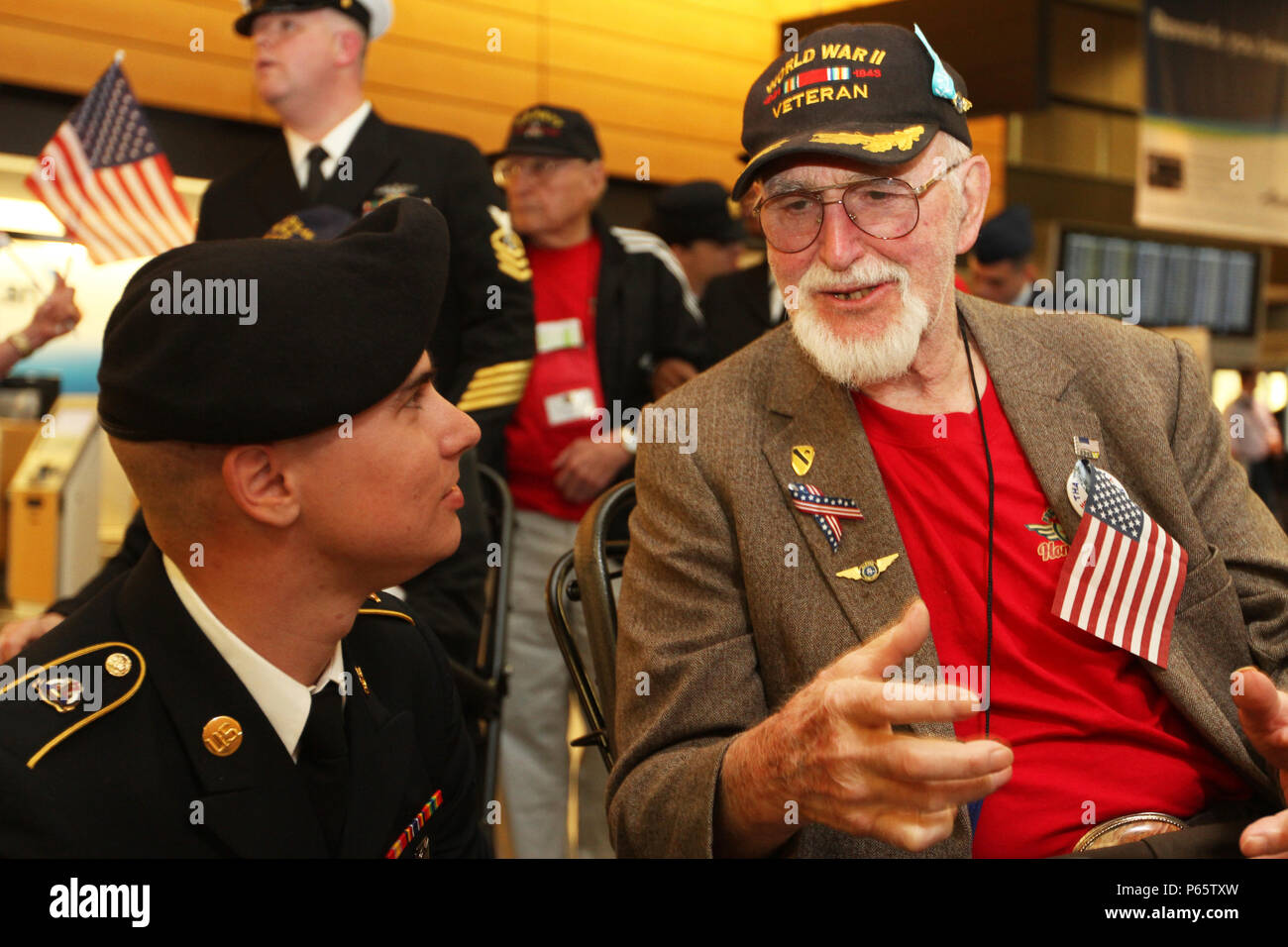 Spc. Paul Kelley, Headquarters and Headquarters Battalion, I Corps, talks with a World War II veteran at Seattle-Tacoma International Airport as part of an Honor Flight May 9. A group of veterans returned from a trip to Washington D.C. to visit memorials honoring their sacrifices. The Honor Flight Network has flown nearly 160,000 veterans to Washington D.C. since 2005. (U.S Army photo by Staff Sgt. Steven Schneider, 5th MPAD) Stock Photo