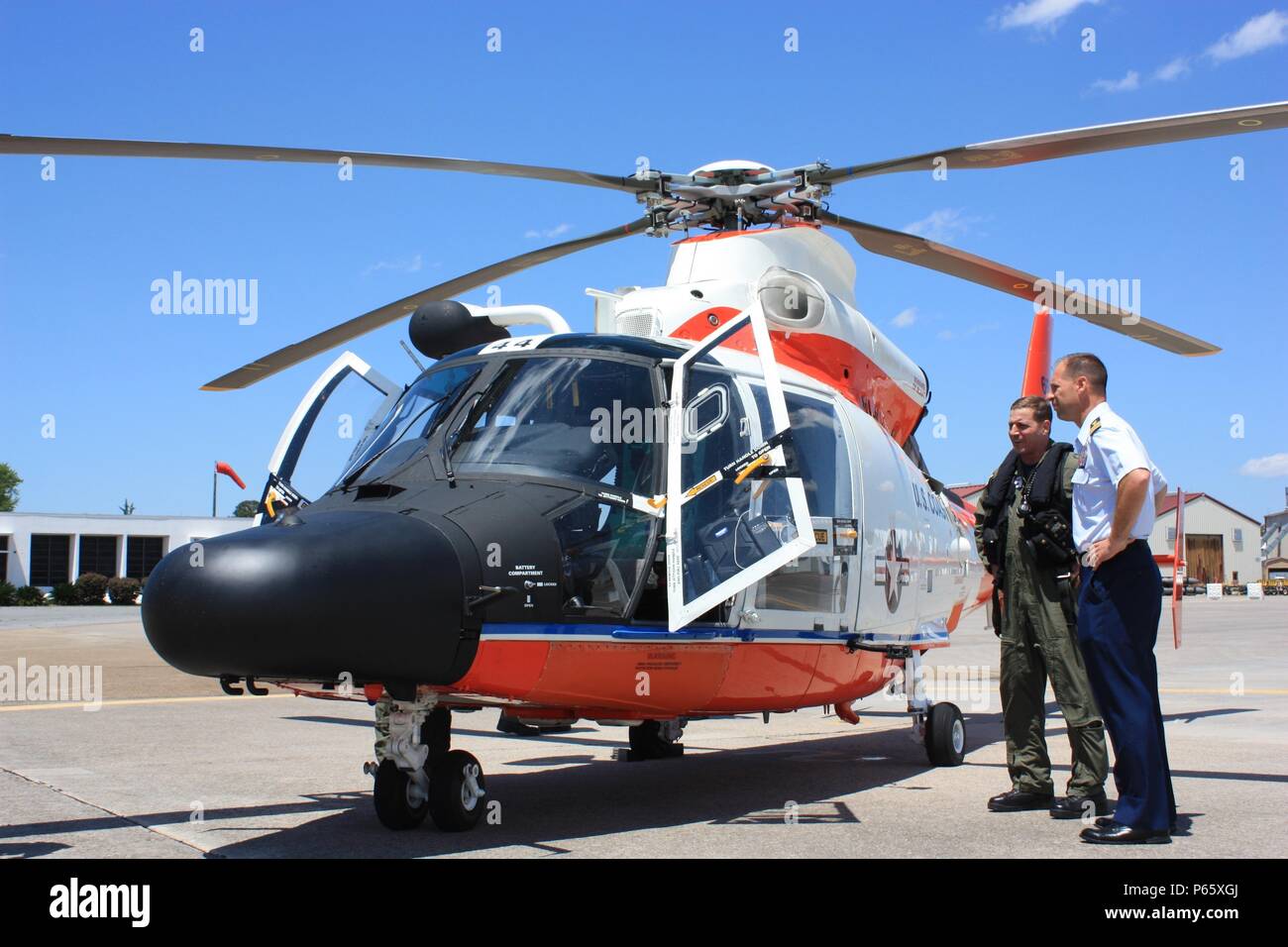 Two Coast Guardsmen stand next to a specially-painted MH-65 Dolphin helicopter, May 4, 2016, at Coast Guard Air Station Savannah, Georgia. The helicopter was flown to the air station as part of the unit’s observance of the Coast Guard’s yearlong celebration of 100 years of aviation. U.S. Coast Guard photo by Lt. Trent Meyers Stock Photo