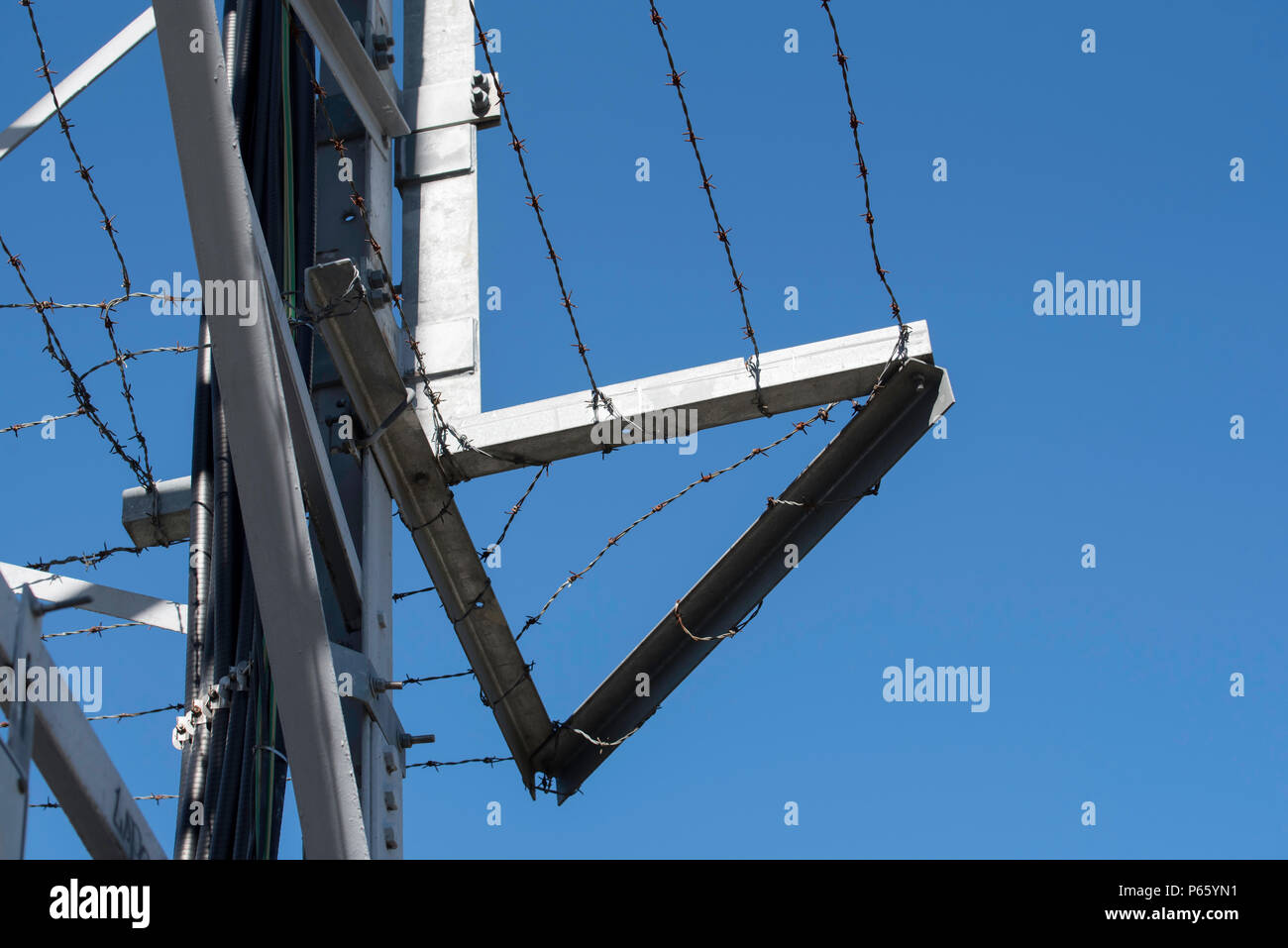 Over hanging barbed wire around a steel 133kv high voltage power tower