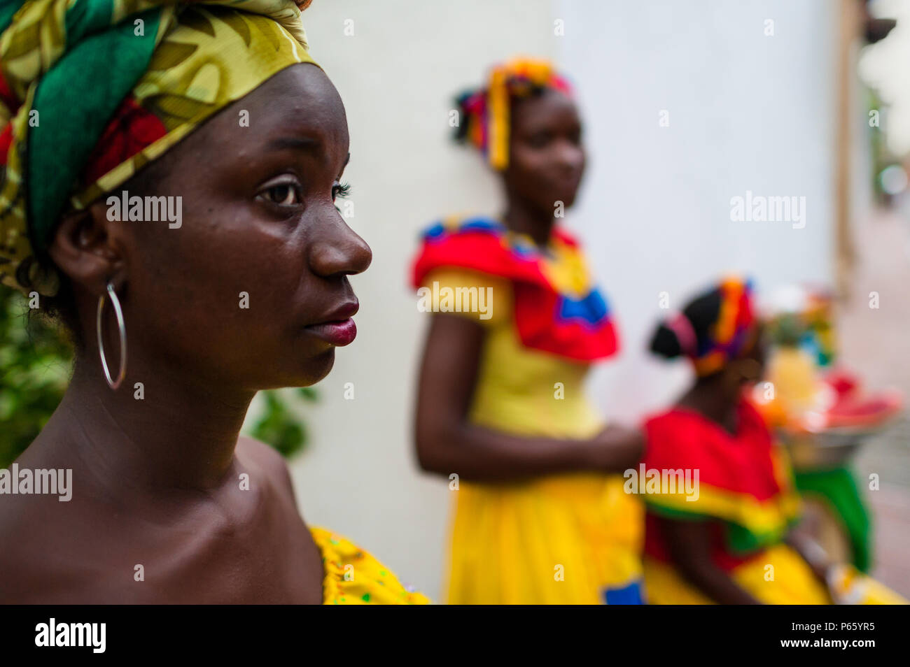 Afro-Colombian women, dressed in the traditional ‘palenquera’ costume, sell fruits on the street of Cartagena, Colombia. Stock Photo