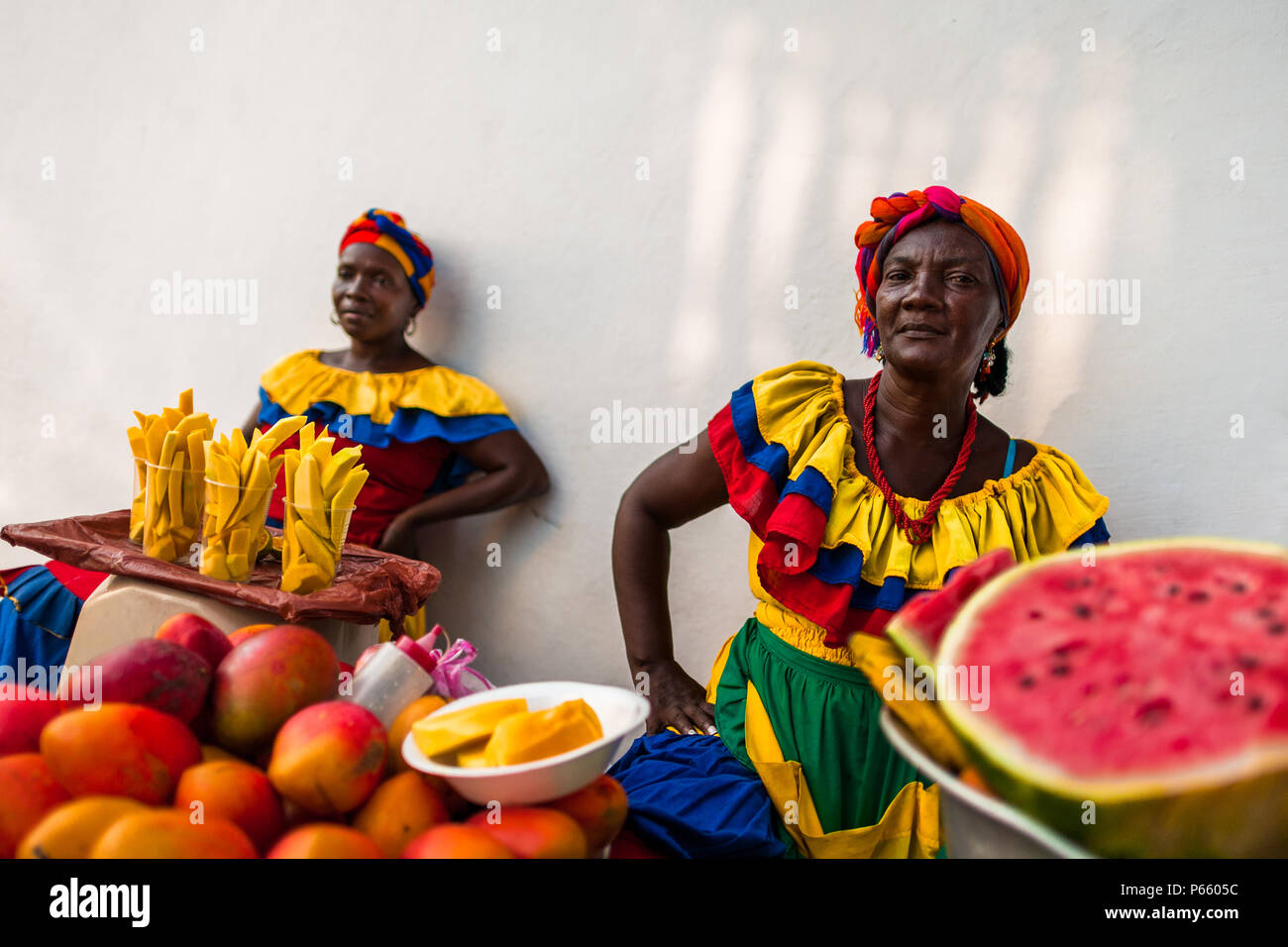 Afro-Colombian women, dressed in the traditional ‘palenquera’ costume, sell fruits on the street of Cartagena, Colombia. Stock Photo