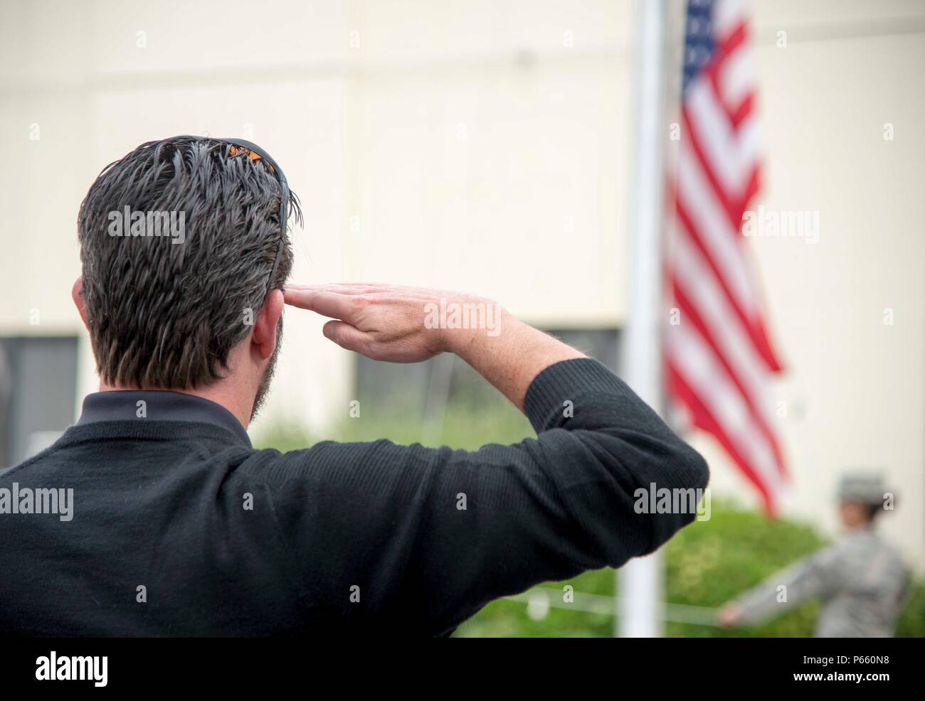 Michael Warrell, Solano First Federal Credit Union president and chief  executive officer and 60th Operations Support Squadron Honorary Commander,  salutes the flag during a Retreat ceremony at the Sgt. Paul P. Ramoneda