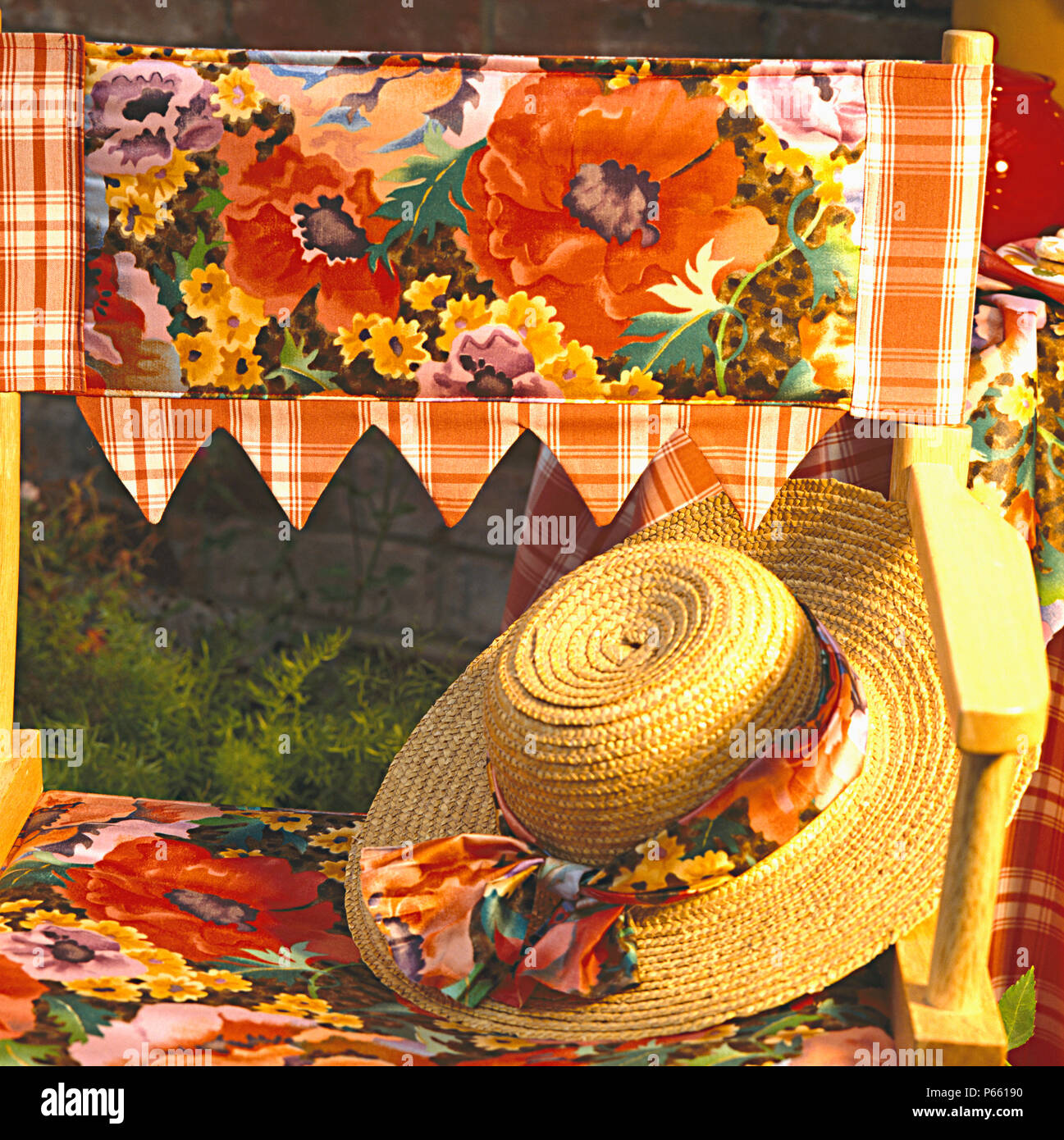 Close-up of straw hat on director's chair with hand-made brightly coloured floral sling and seat Stock Photo