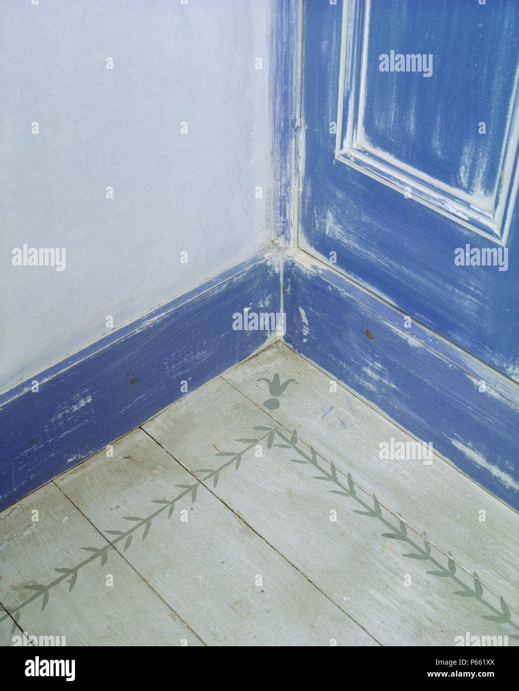 Closeup of stencilled floorboard and blue distressed paint effect door