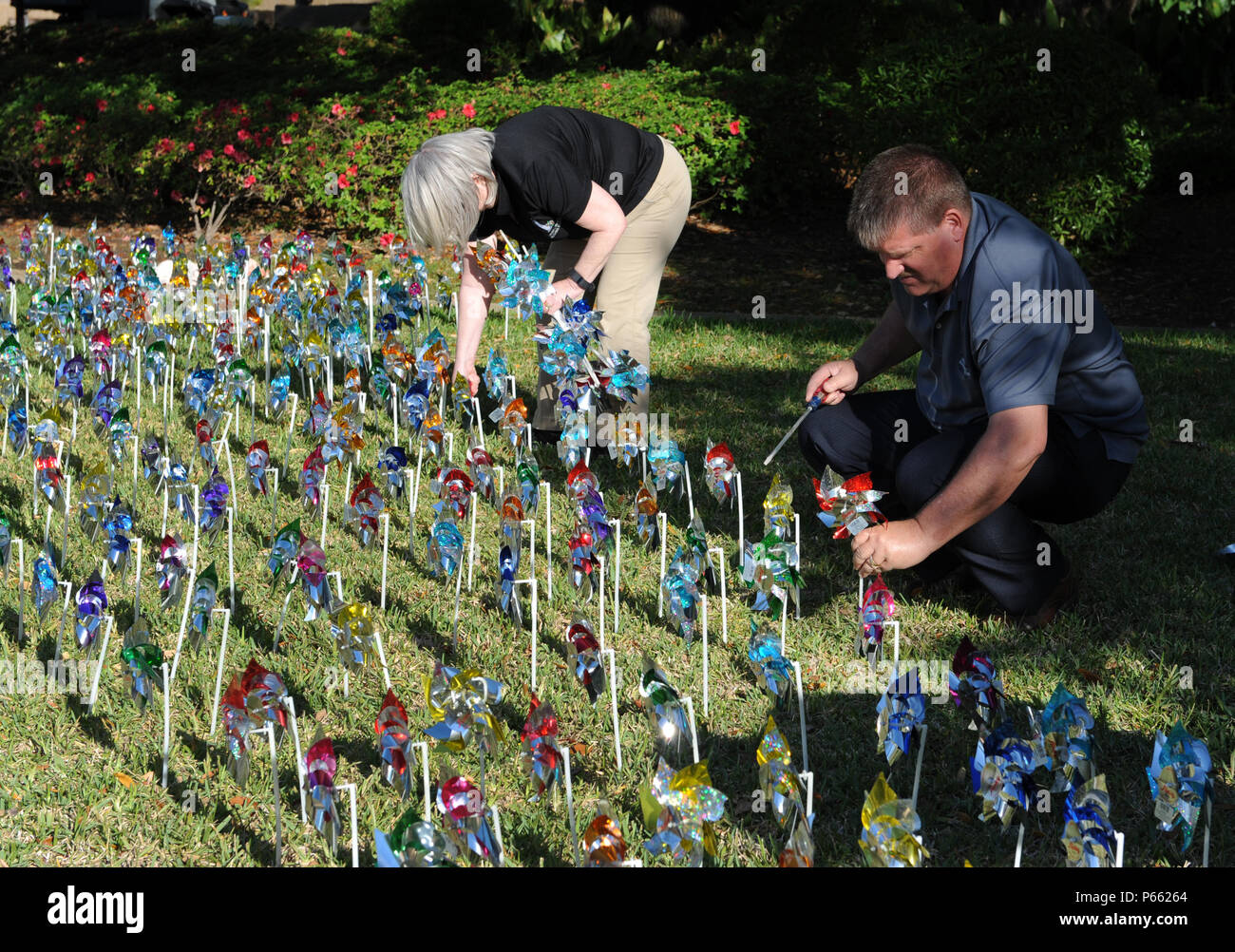 Jackie Pope, 81st Force Support Squadron airman and family readiness center chief, and John Lowe, 81st FSS community readiness consultant, place pinwheels into the ground in front of the Keesler Medical Center April 4, 2016, Keesler Air Force Base, Miss. Members of the 81st Medical Operations Squadron family advocacy and volunteers placed pinwheels to individually represent children in Harrison and Hancock counties who were victims of child abuse or neglect last year. (U.S. Air Force photo by Kemberly Groue) Stock Photo
