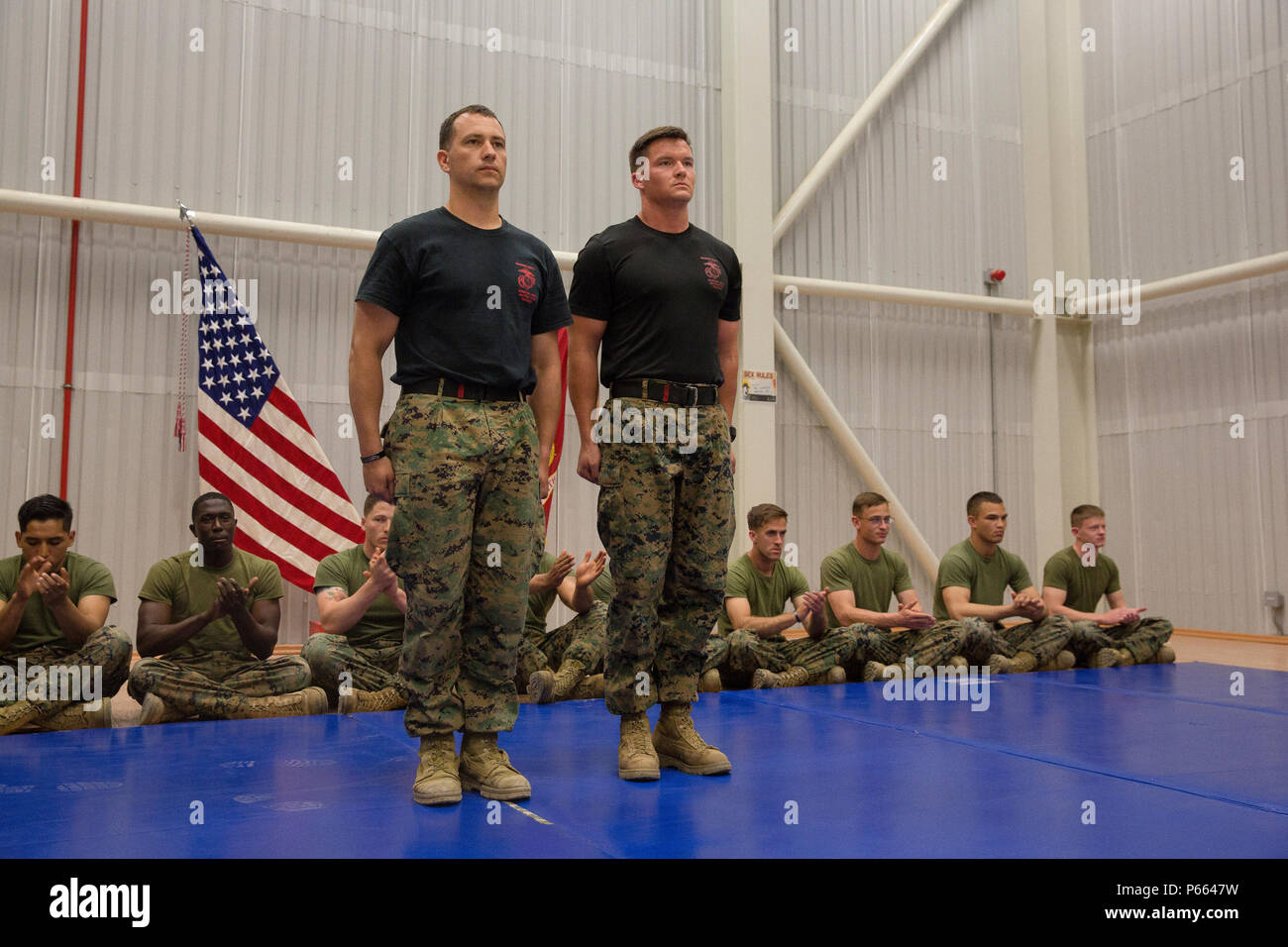 U.S. Marine Corps 1st Lt. Thomas A. White, an infantry officer, and Staff Sgt. Benjamin L. Tupaj, a joint terminal attack controller, both with Black Sea Rotational Force, stand at the position of attention as they are recognized by Marines and sailors for their hard work as the Marine Corps Martial Arts Instructor Trainers of class 155-16. The instructors stressed to the students over the weeks that an equal growth of their mental, character and physical disciplines are essential as a Martial Arts Instructors. (U.S. Marine Corps photo by Cpl. Kelly L. Street, 2D MARDIV COMCAM/Released) Stock Photo