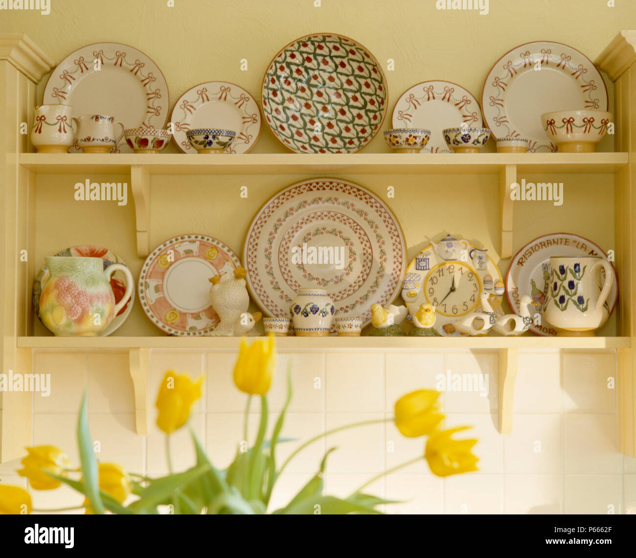Closeup of collection of pottery plates and jugs on cream shelves