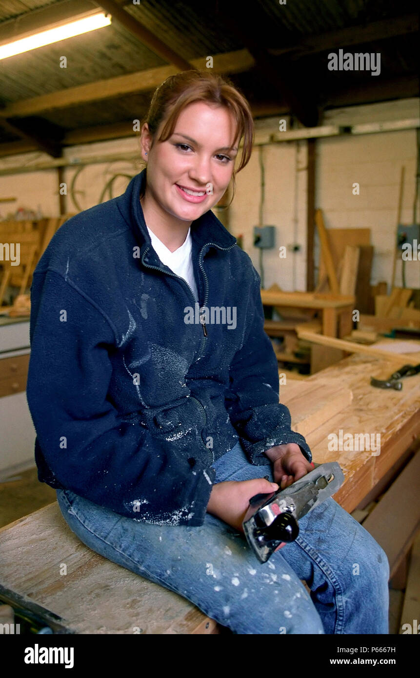 Woman carpenter in workshop looking at camera and holding a smoothing plane Stock Photo