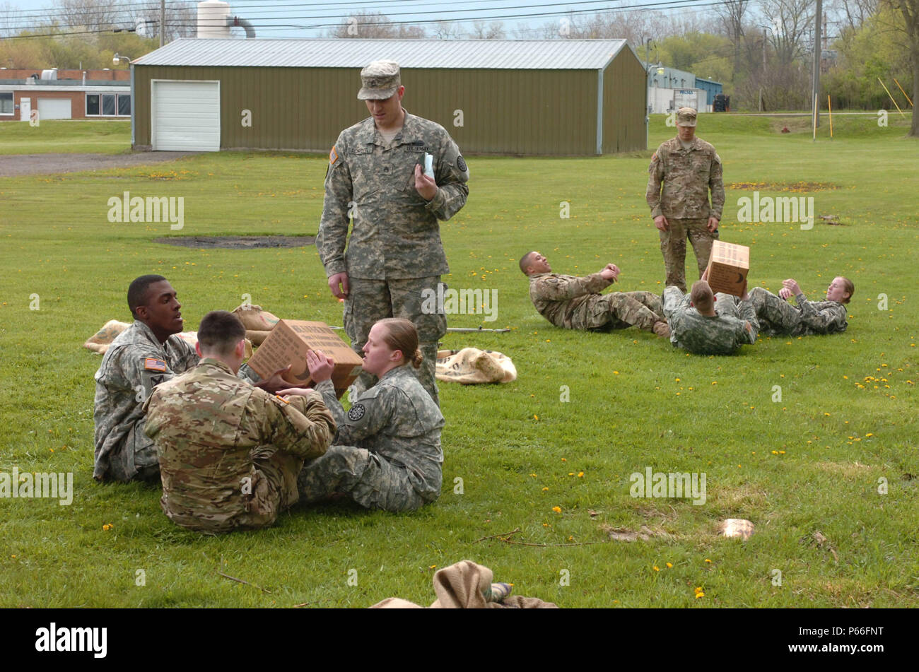 Soldiers of the 144th Military Police Company, 210th MP Battalion, 177th MP Brigade, Michigan National Guard, compete in the Meal Ready to Eat sit-up portion of the Blackhats' Last Charge held in Corunna, Mich., May 7, 2016. The Blackhats' Last Charge is a competition in which Soldiers compete in three-person teams against each other through a three-mile road march and a series of physical team events that include a Sackman's race, tow bar carries, tow bar squats, an arm chair carry, team triangle push-ups, burpees, and a HMMWV push. The 144th MP Co. is being divested as part of a force struct Stock Photo