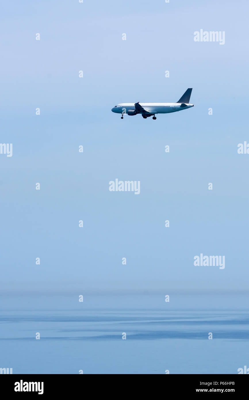 The plane flying over the sea is preparing to land Stock Photo