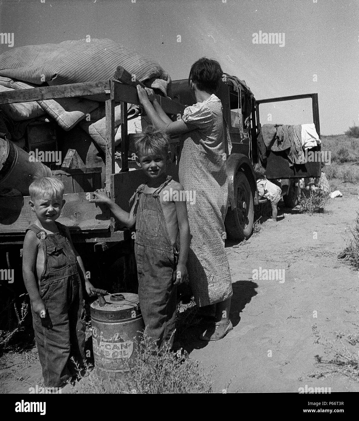 Part of an impoverished family of nine on a New Mexico highway. Depression refugees from Iowa. Left Iowa in 1932 because of father's ill health. Father an auto mechanic labourer, painter by trade, tubercular. Family has been on relief in Arizona but refused entry on relief roles in Iowa to which state they wish to return. Nine children including a sick four-month-old baby. No money at all. About to sell their belongings and trailer for money to buy food. 'We don't want to go where we'll be a nuisance to anybody' 1936 Stock Photo