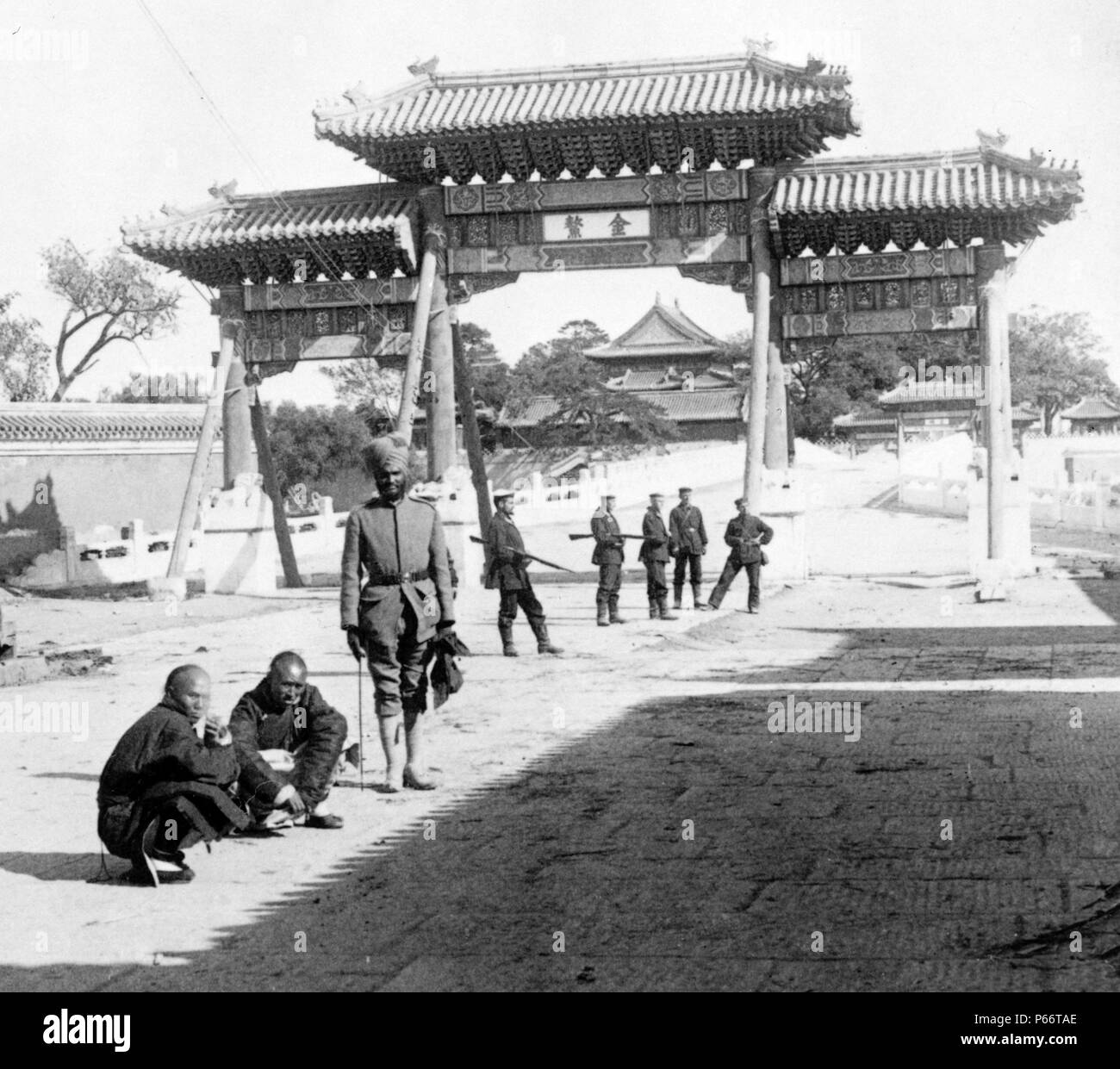 east over Marble Bridge toward the Forbidden City, Peking, 1901. photographic print on stereo card, Indian soldiers and two Chinese men in front of a gate. Stock Photo