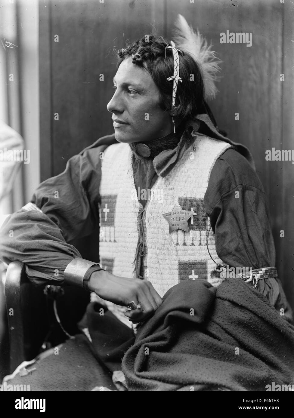Unidentified American Indian by Photographer Gertrude Käsebier, 1852-1934. American Indian man, member of Buffalo Bill's Wild West Show, seated, facing left, wearing star-shaped badge reading: Buffalo Bill's Wild West Co. Police. Dated ca. 1900 Stock Photo