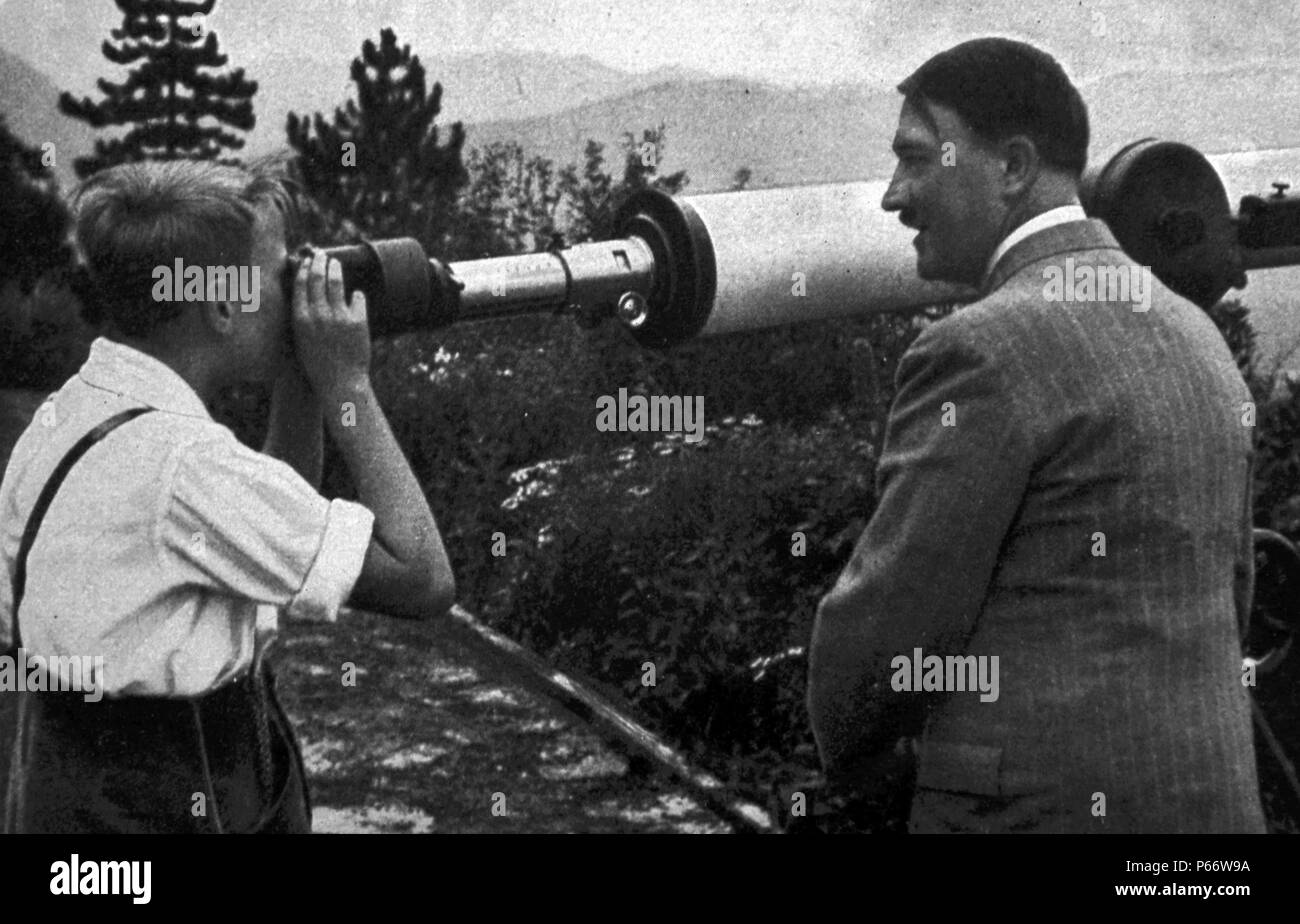 Adolf Hitler 1889-1945. addresses a rally 1936. German politician and the leader of the Nazi Party. He was chancellor of Germany from 1933 to 1945 and dictator of Nazi Germany from 1934 to 1945. Seen here with a young boy looking through a telescope at his mountain retreat. Stock Photo