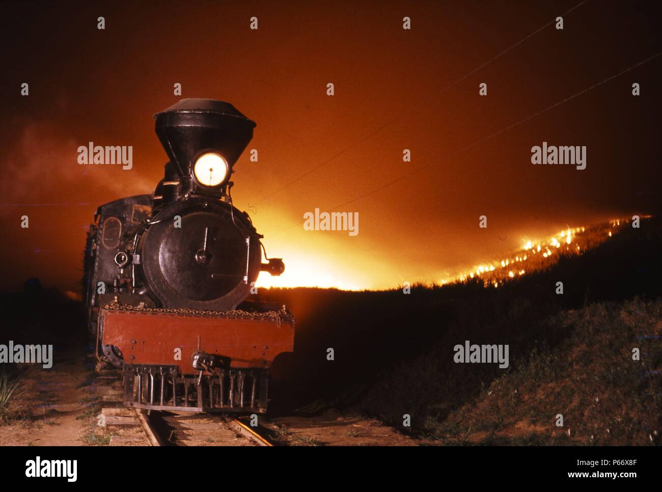 A typically British 4-6-0 built by Robert Stephenson at Newcastle Upon Tyne in 1906, leads a train through blazing fields. In sugar plantation service Stock Photo