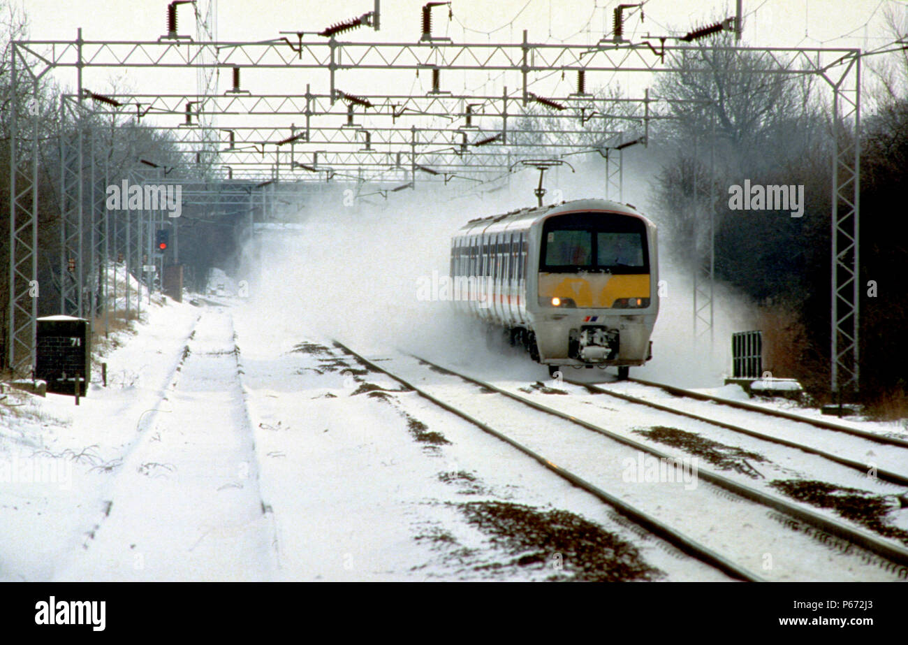 A train powers along a snow covered railway. Stock Photo