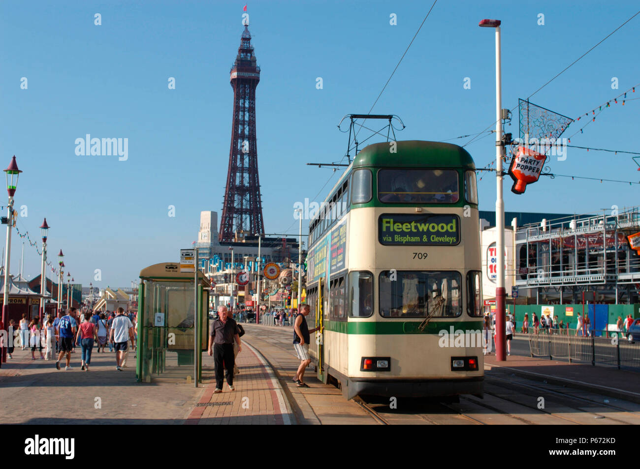 A typical scene on Blackpool seafront as one of the resort's heritage trams traverses the promenade with the famous Blackpool Tower in the background. Stock Photo