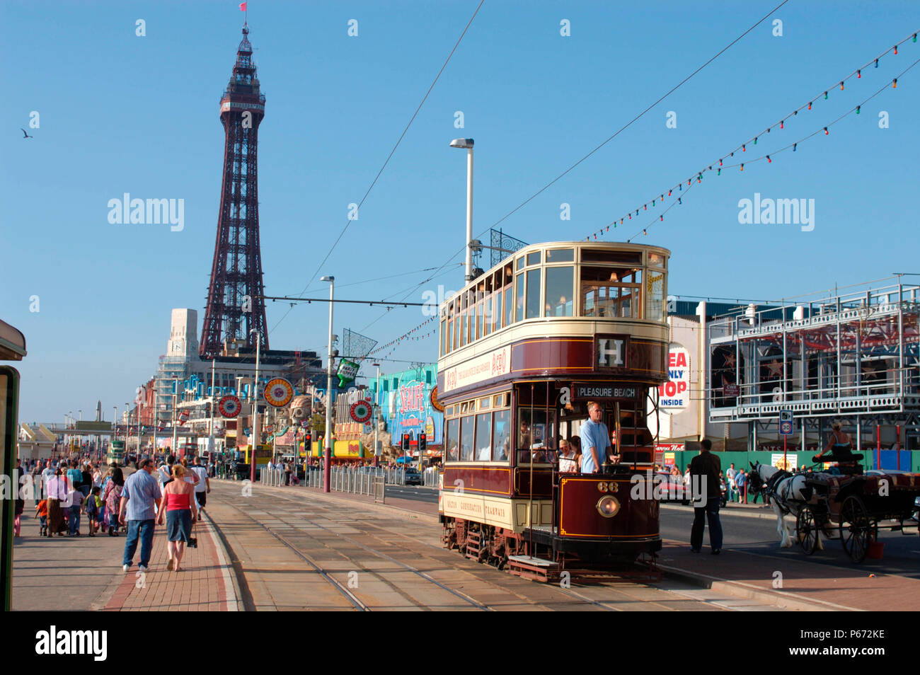 A typical scene on Blackpool seafront as one of the resort's heritage trams traverses the promenade with the famous Blackpool Tower in the background. Stock Photo