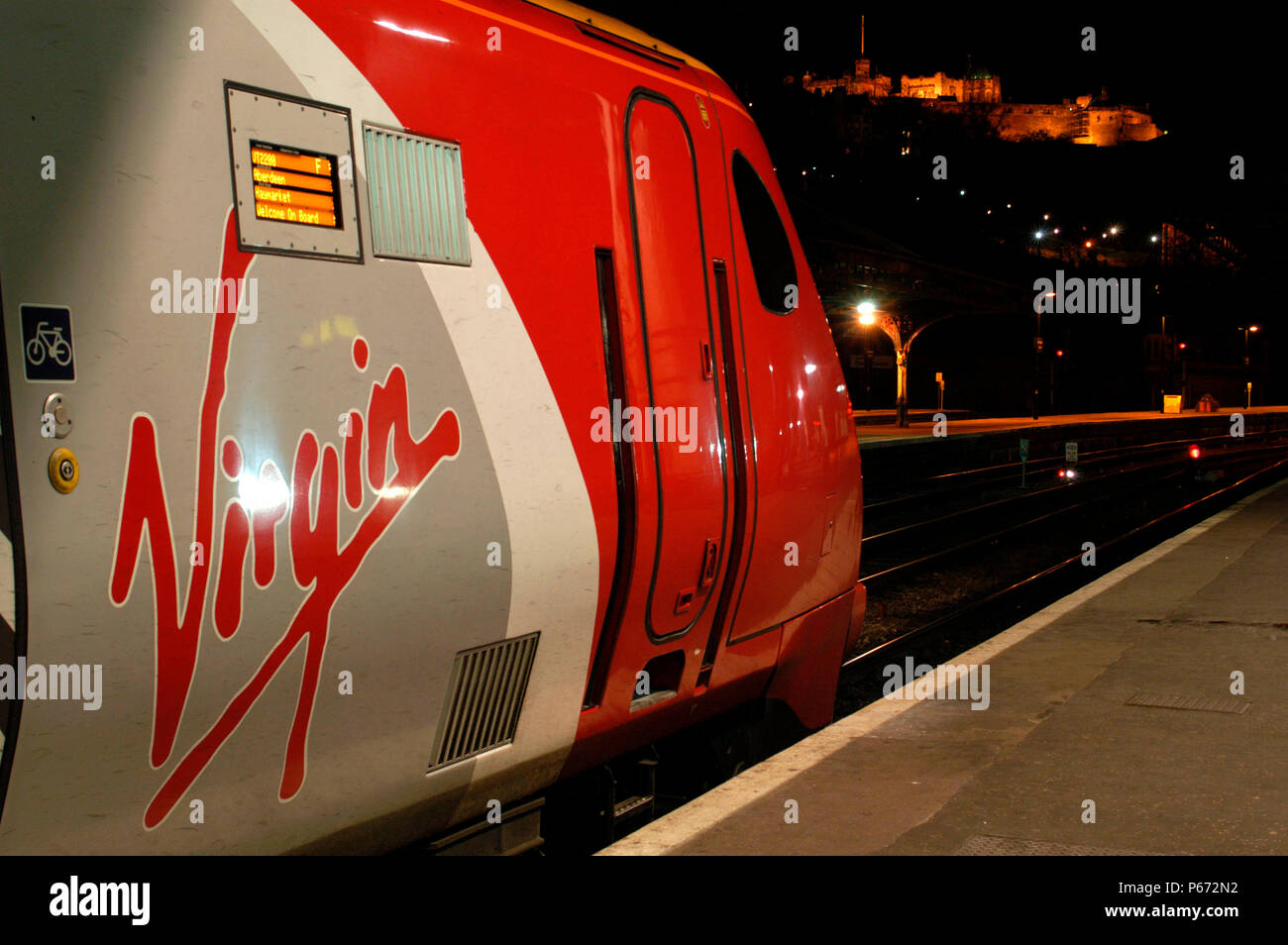 A Virgin Trains Cross Country Edinburgh to Aberdeen service awaits night departure from Edinburgh Waverly station with Edinburgh Castle in the backgro Stock Photo