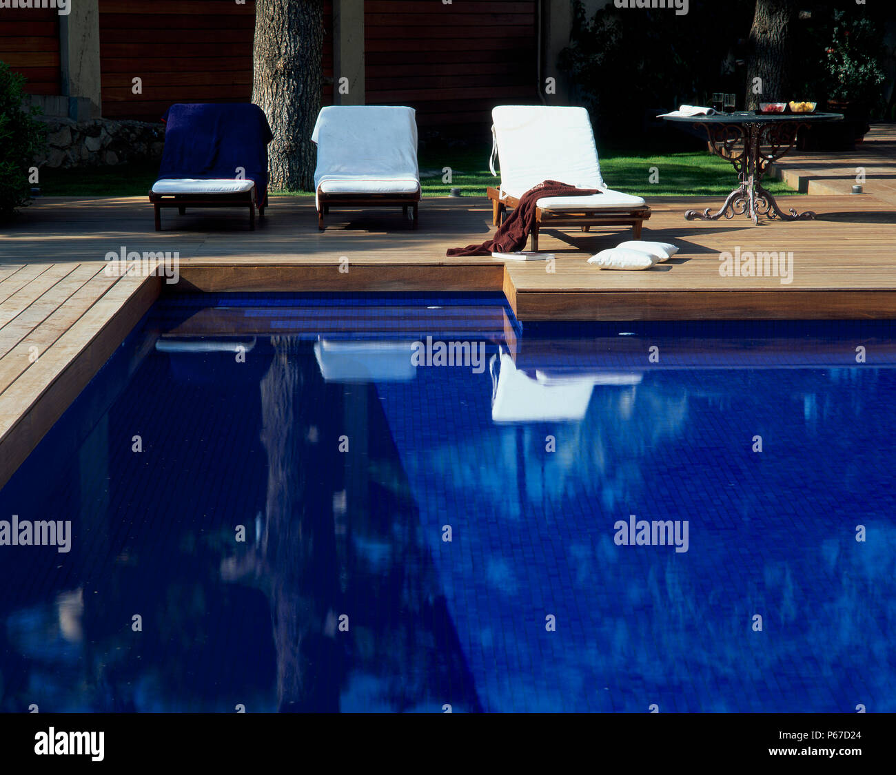 View of deck chairs beside a clear swimming pool Stock Photo Alamy