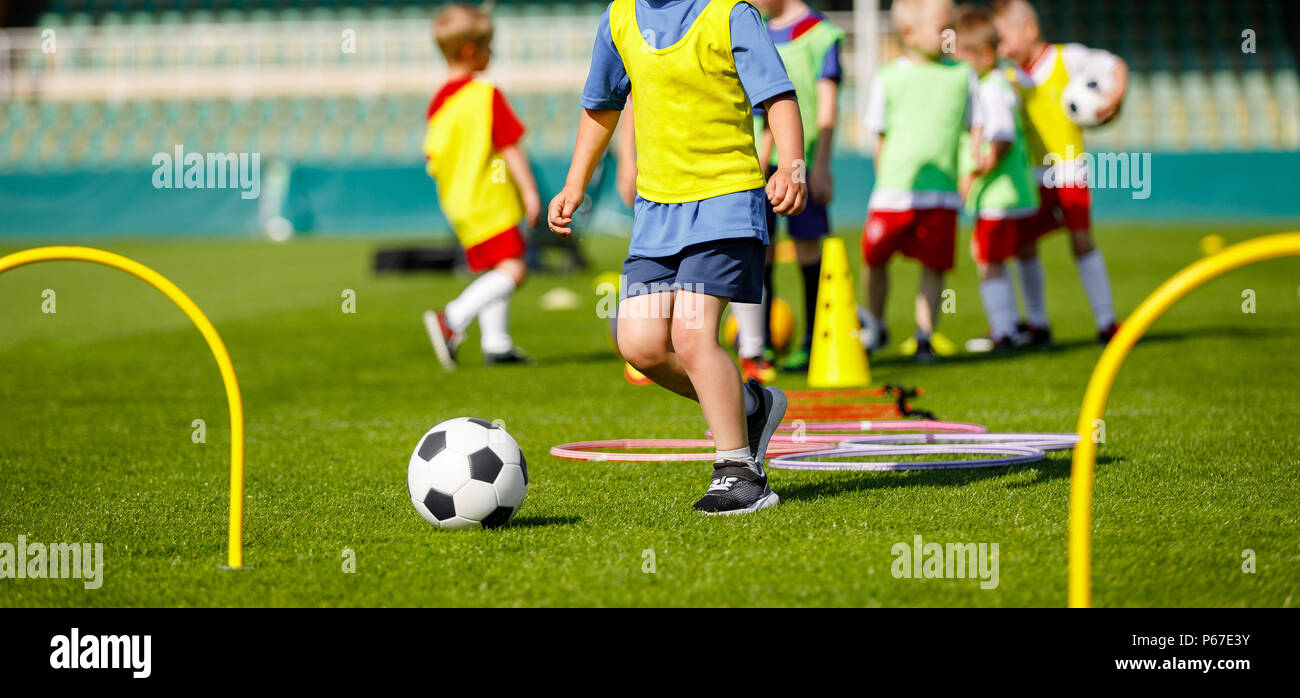 Kid Young Athletes Training with Football Equipment. Football Speed and Agility Training. Young Footballer in Blue Sportswear at Training Session on G Stock Photo