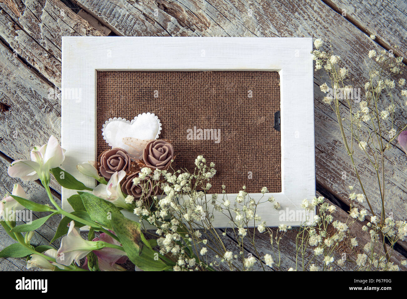 Blank photo frame and white flowers over wooden table background Stock Photo