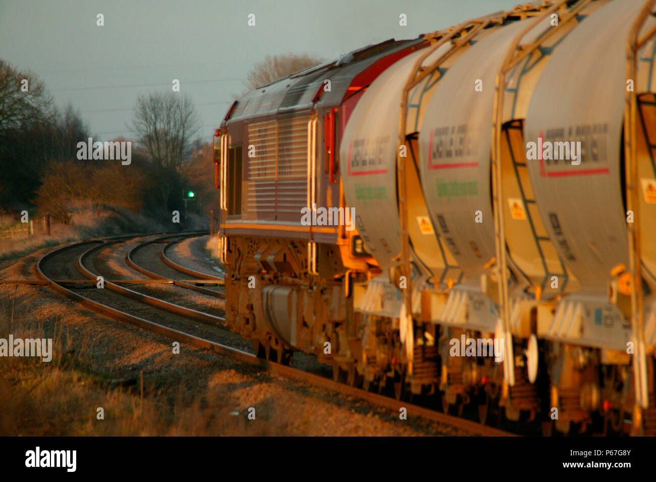 In The Golden Glow Of The Early Evening Sun An Ews Class 66 Heads A Rake Of Cement Hoppers Through Rearsby In The Leicestershire Countryside March Stock Photo Alamy