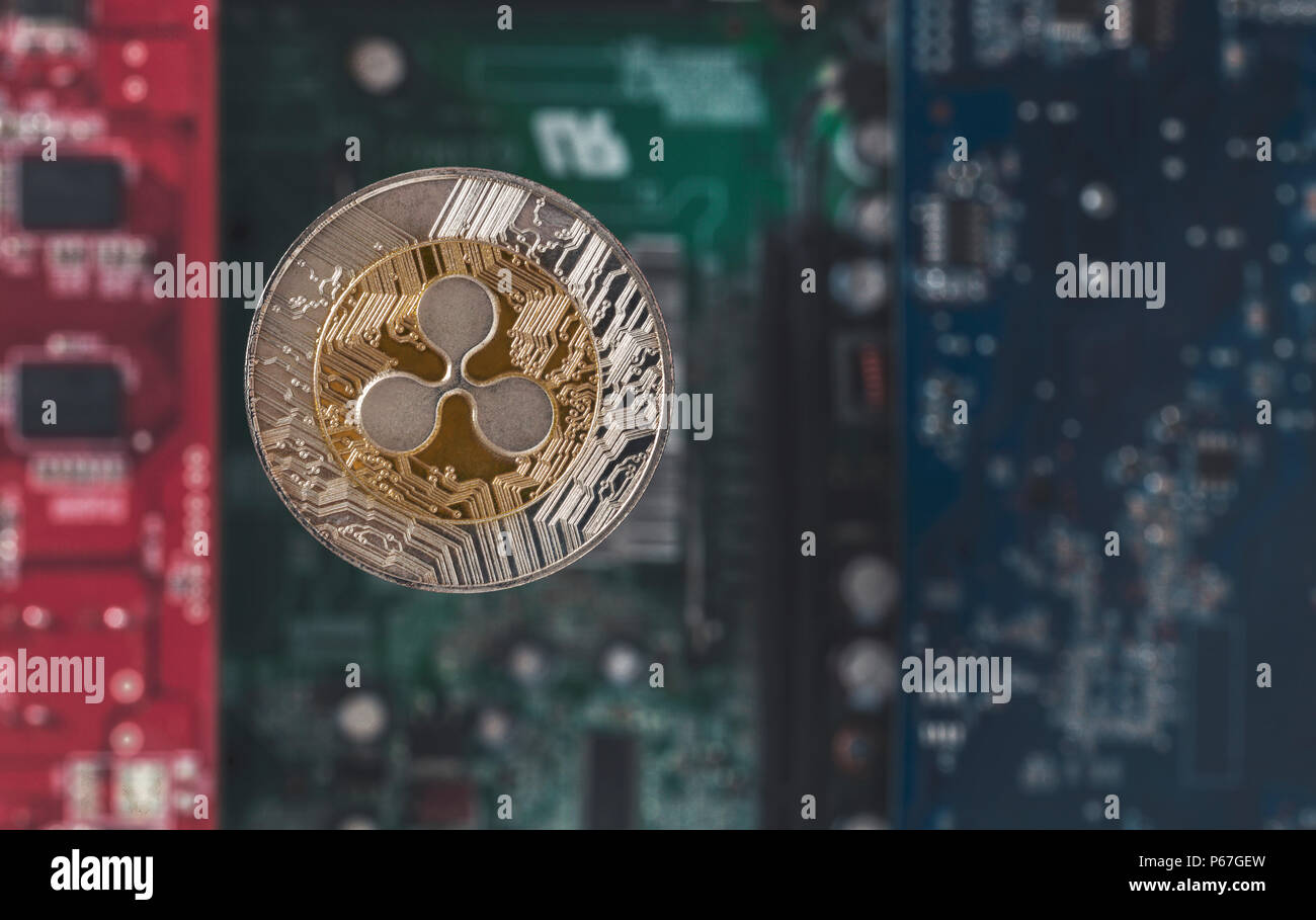 Gold silver Ripple coin on blurry background of electronical components as digital money concept Stock Photo