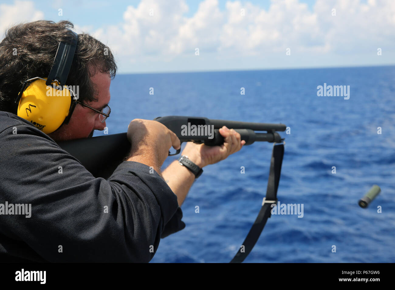 160509-N-IX266-011 SOUTH CHINA SEA—Civilian mariner Michael P. McAlister, able body seaman of the fleet replenishment oiler USNS John Ericsson (T-AO 194), fires a shotgun during a small-arms weapons qualification course here, May 5. (U.S. Navy photo by Grady T. Fontana/Released) Stock Photo