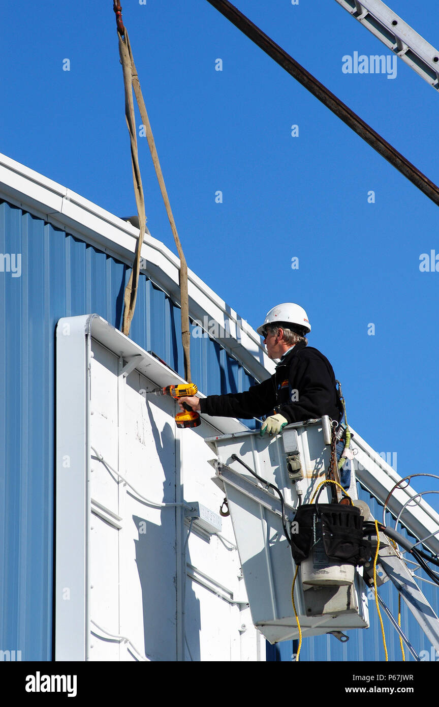 Construction worker installing signage in lift, on warehouse BBS