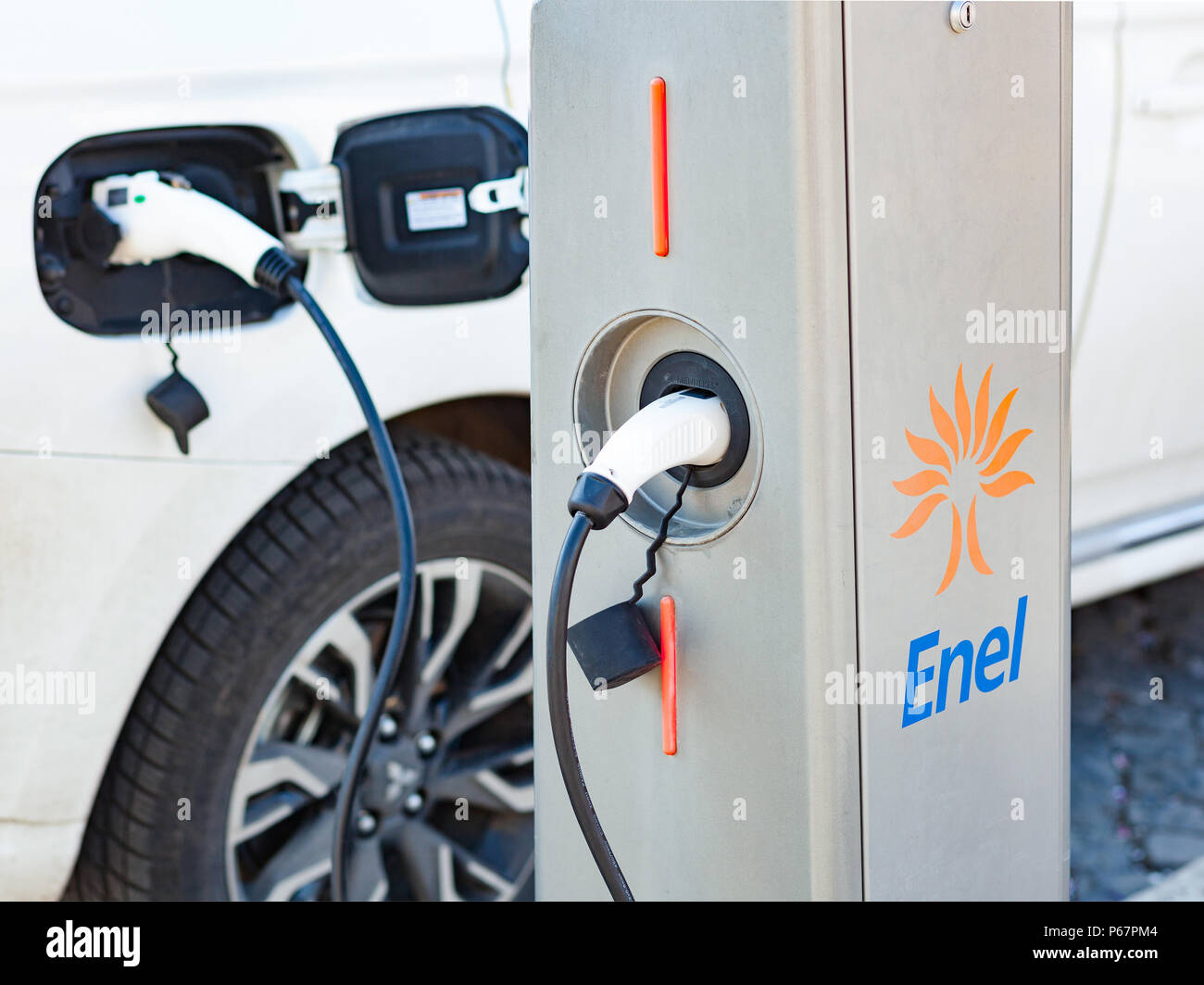 Roma, Italy - February 11, 2018: Enel electric car charger plugged in to the socket.The modern electric car charging the battery. Stock Photo