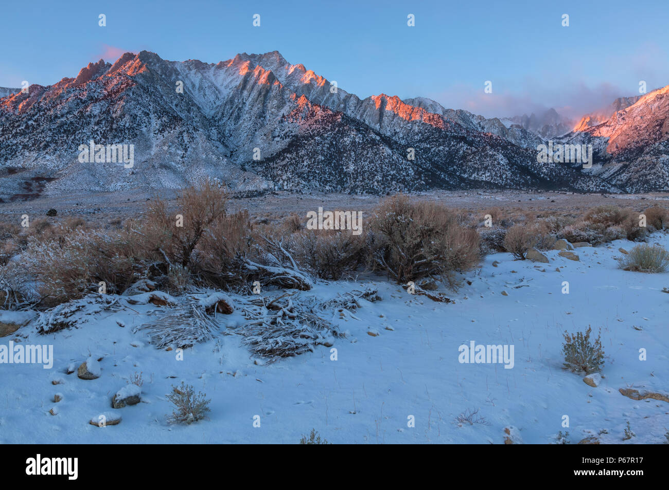 Morning sunlight reflected on the Lone Pine Peak, with Mt. Whitney partially covered with fog, after a late November snow storm, Lone Pine, California. Stock Photo