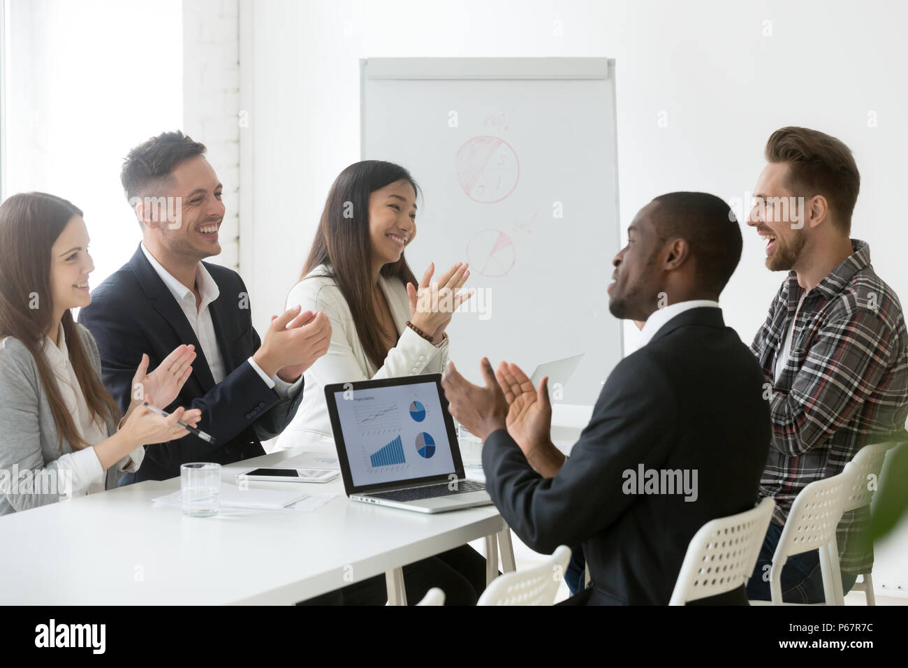 Excited diverse team applauding celebrating shared goal achievem Stock Photo