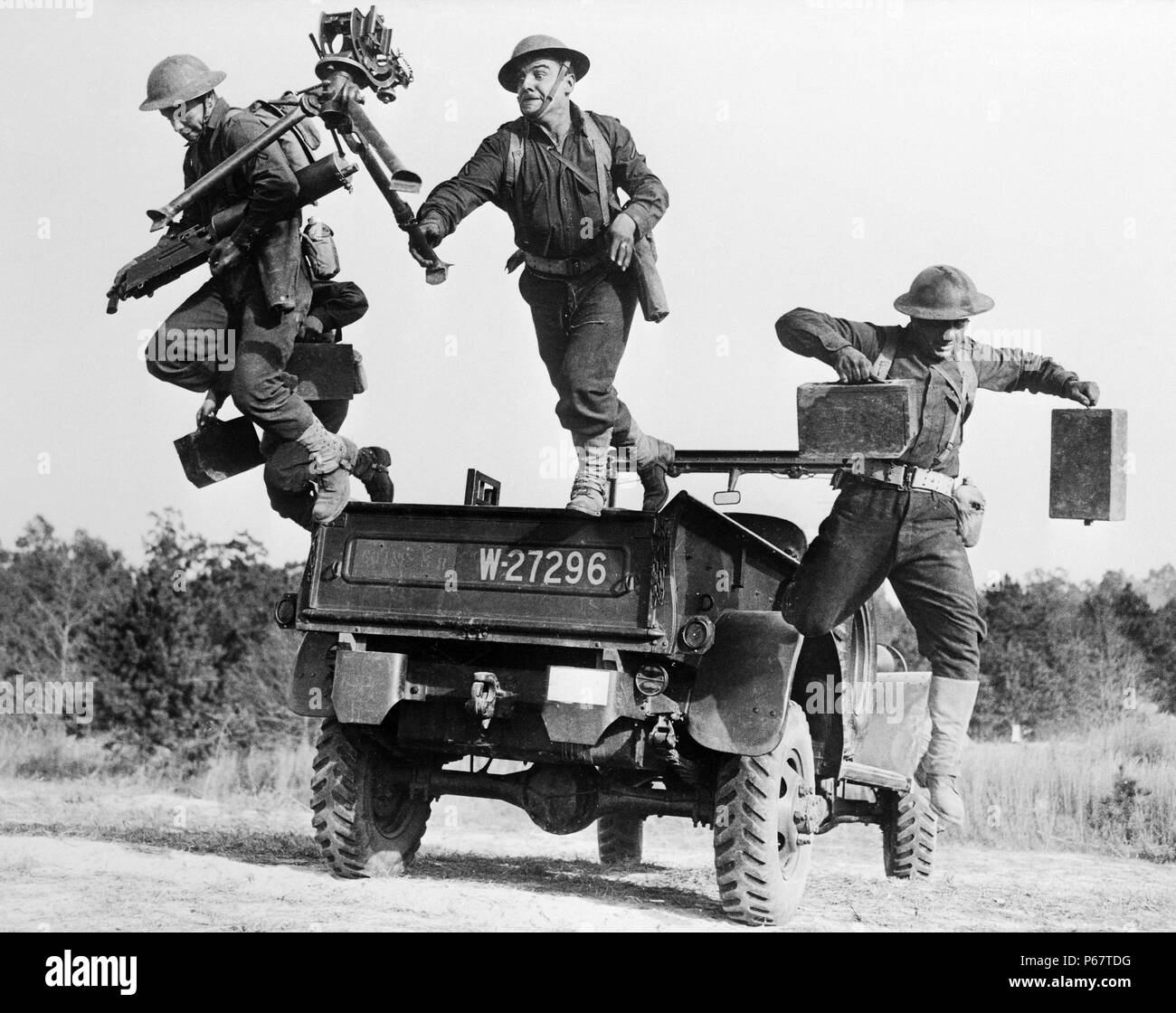 An American M1917 Browning machine gun squad in the middle of jumping off the back of a truck, c. 1941 Stock Photo