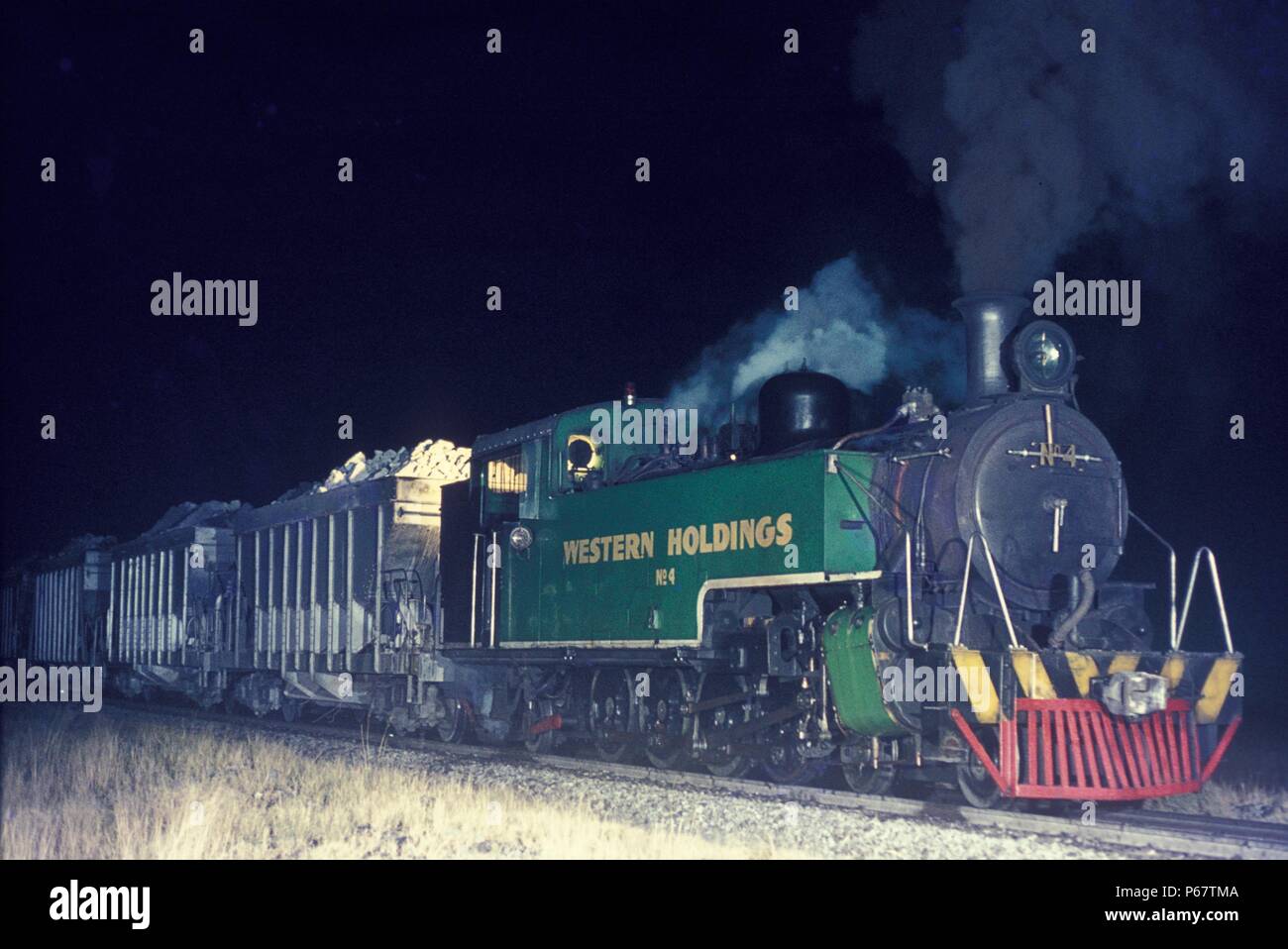 South African gold fields by night. A North British of Glasgow built 4-8-2T hauling a rake of gold ore at Welkom from No.2 shaft to the reduction plan Stock Photo